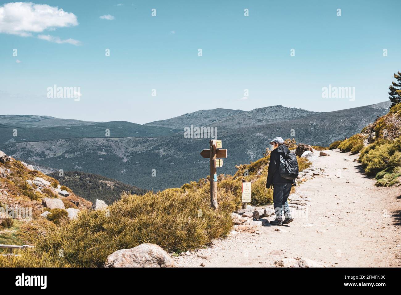 Escursionista in montagna con zaino e maschera di lettura indicazioni. Foto orizzontale. Foto Stock