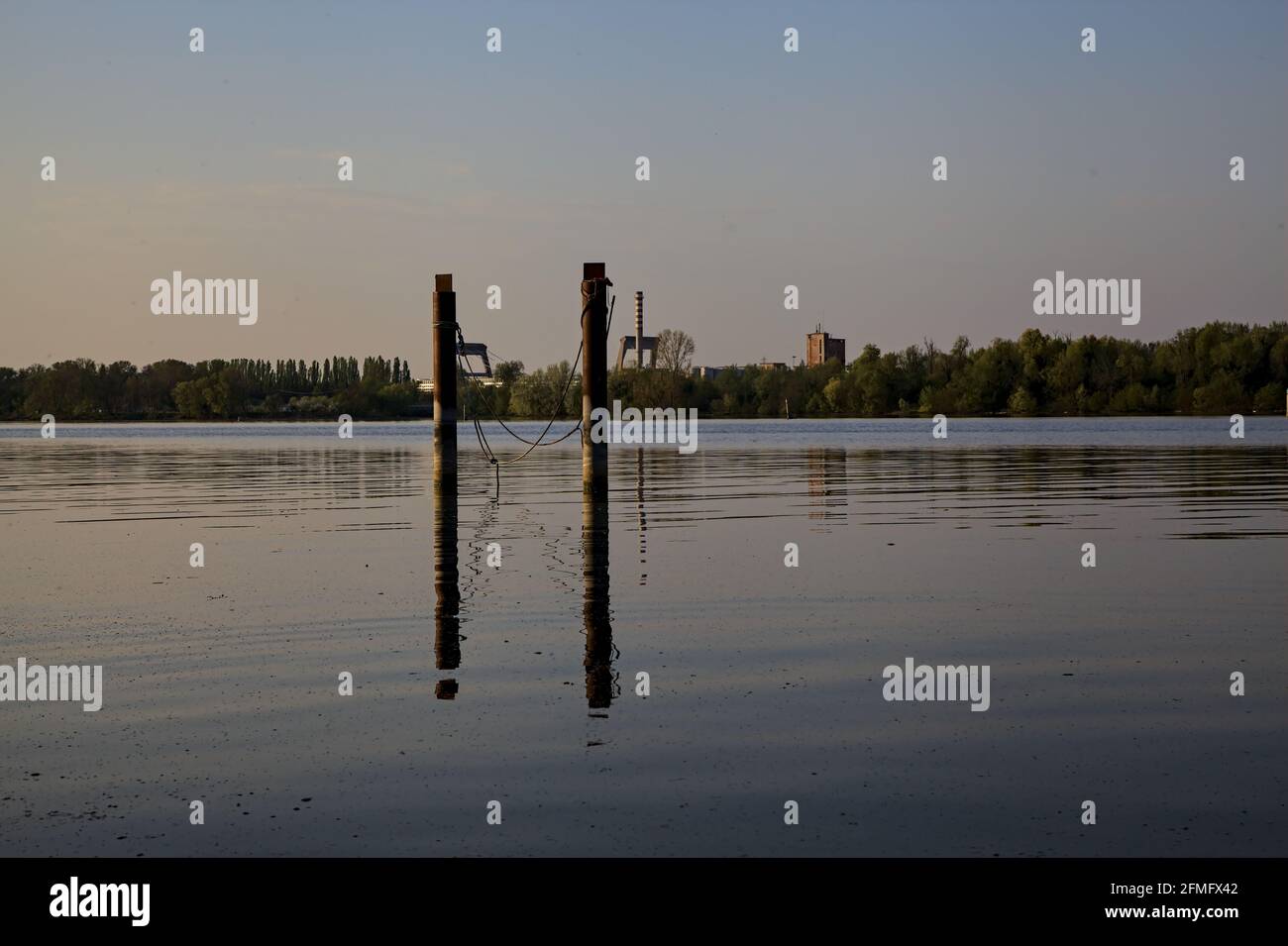 Pali di un ormeggio su un lago con riflessi casted in acqua Foto Stock