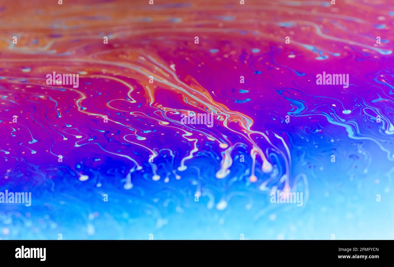 Macro di coloratissime superfici di sapone piano iridescenti con colori fluide iridescenti e modelli astratti e forme, sfondo futuristico dell'arte spaziale Foto Stock