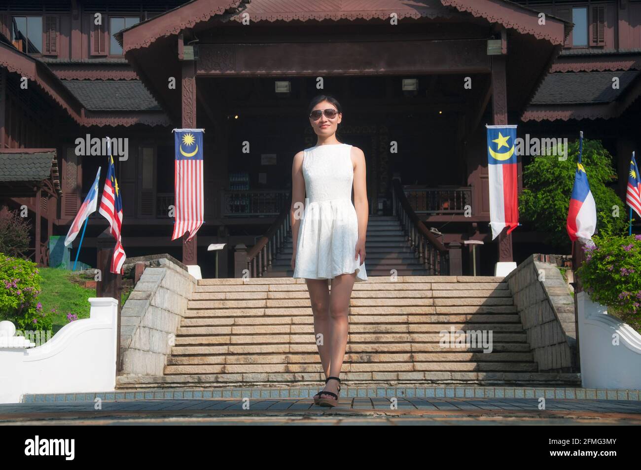 Una donna cinese sorridente che si trova di fronte all'ingresso del museo del palazzo del sultanato di melacca in una soleggiata giornata estiva a Melaka, Malesia. Foto Stock