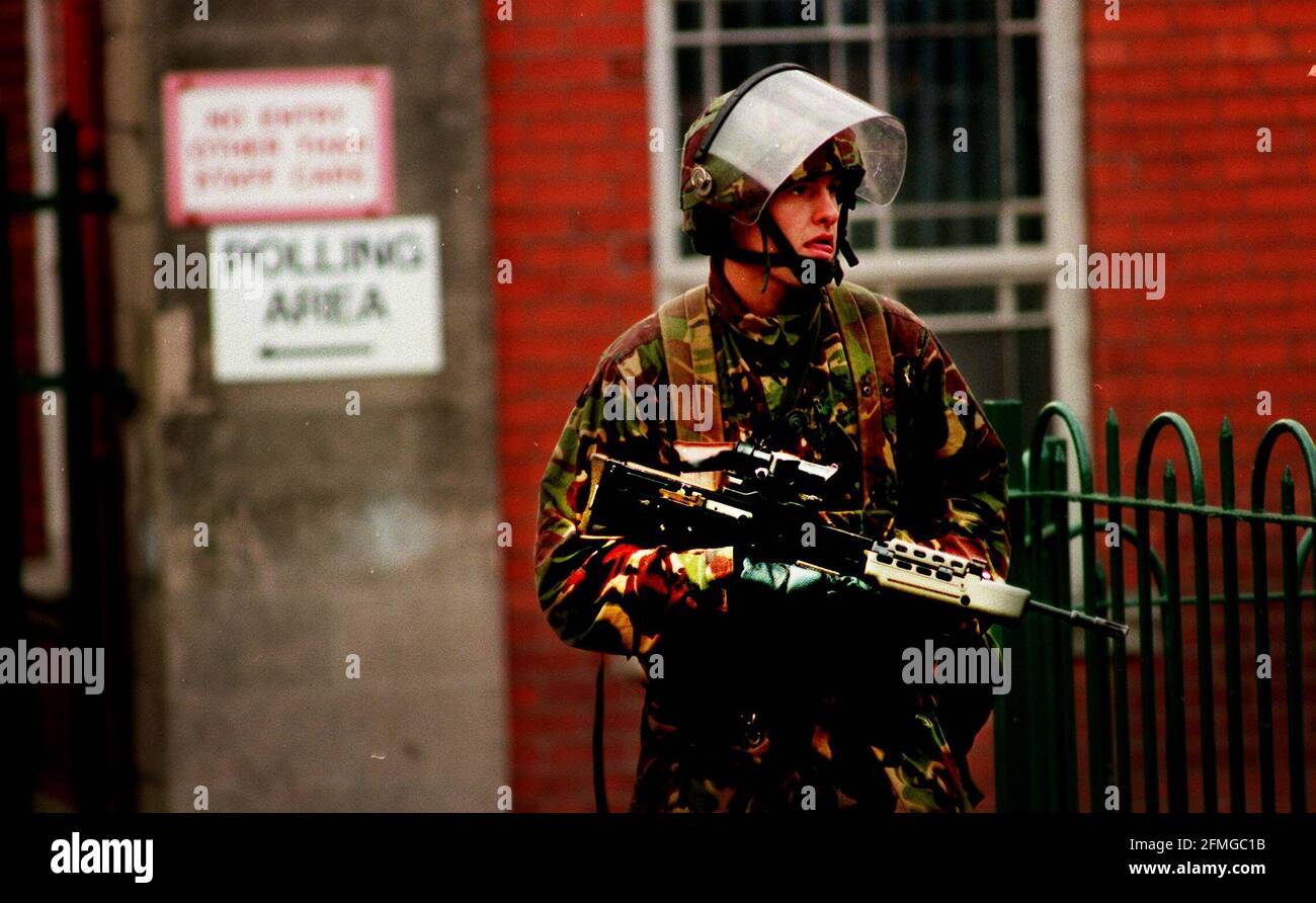 Un soldato dell'esercito britannico a sostegno della guardia di polizia della RUC Al di fuori di una stazione di polling a Falls Road in Nationalist West Belfast Irlanda del Nord durante il referendum per la pace di Ulster Foto Stock