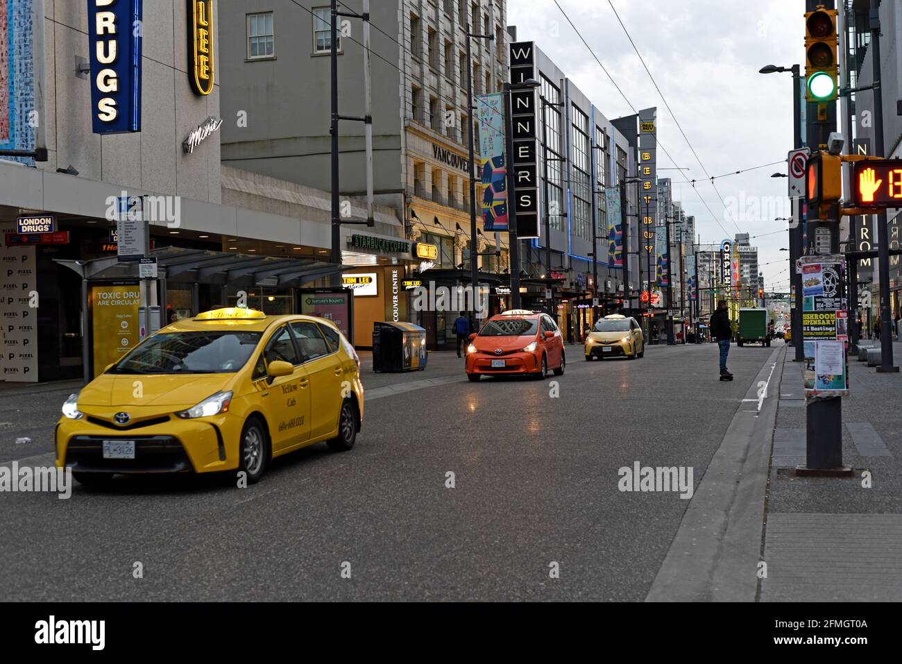 Taxi e un skate boarder si fanno strada lungo Granville Street al crepuscolo a Vancouver, British Columbia, Canada Foto Stock