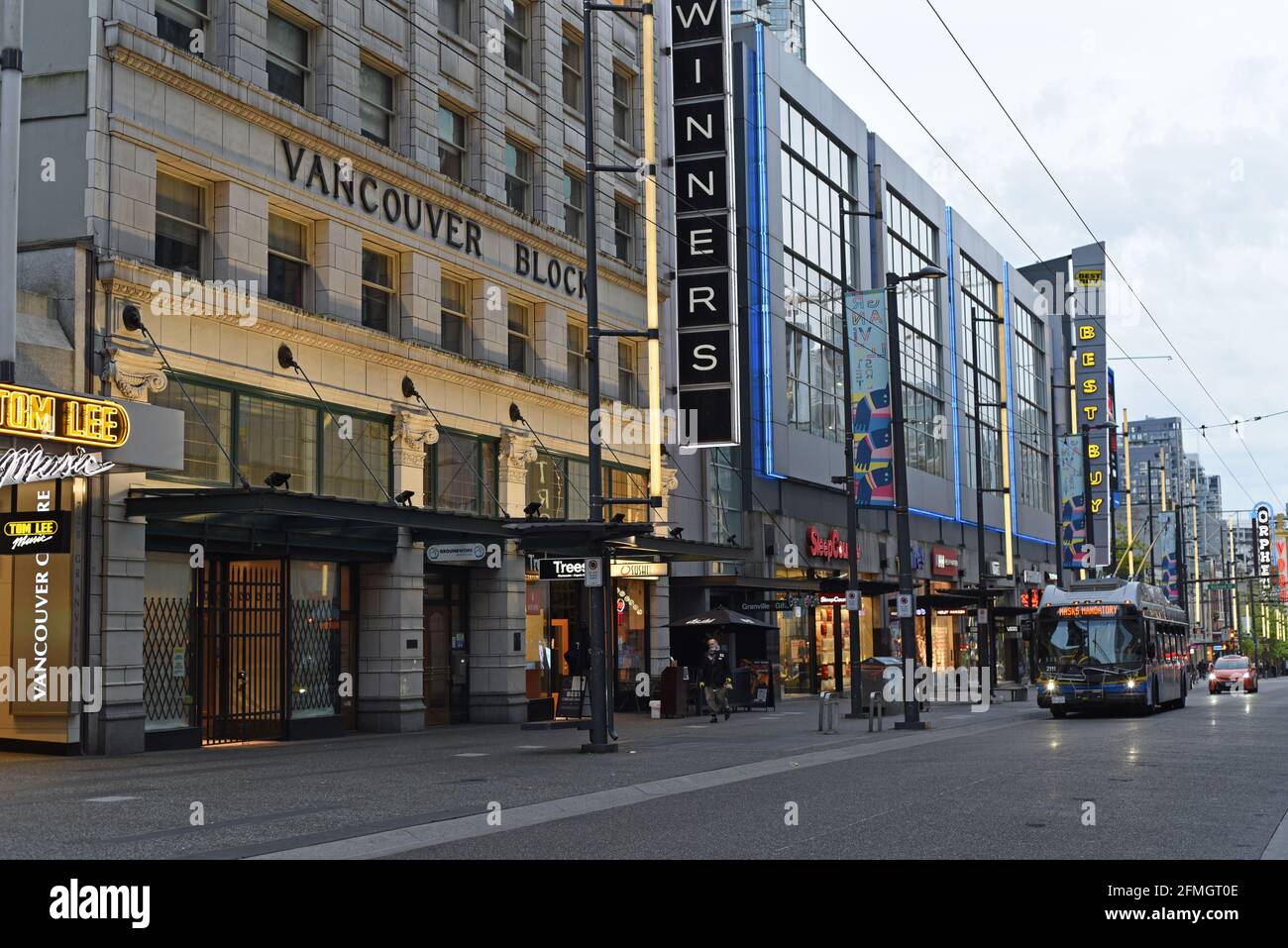 Un autobus cittadino e un taxi fanno la loro strada lungo Granville Street al crepuscolo a Vancouver, British Columbia, Canada Foto Stock