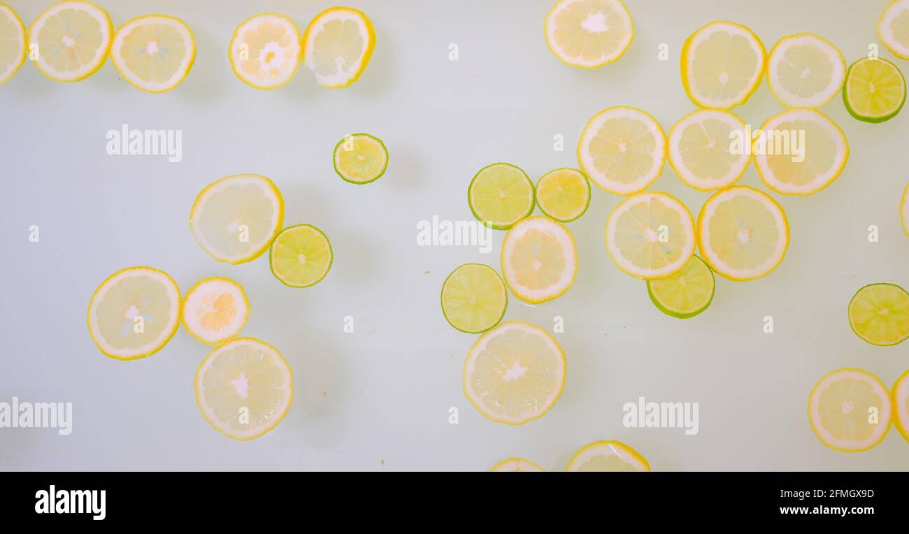 Acqua torbida saponata nel bagno con fette di limone e lime vista dall'alto in full frame. Agrumi. Centro benessere con latte nel bagno per ringiovanire. Foto Stock