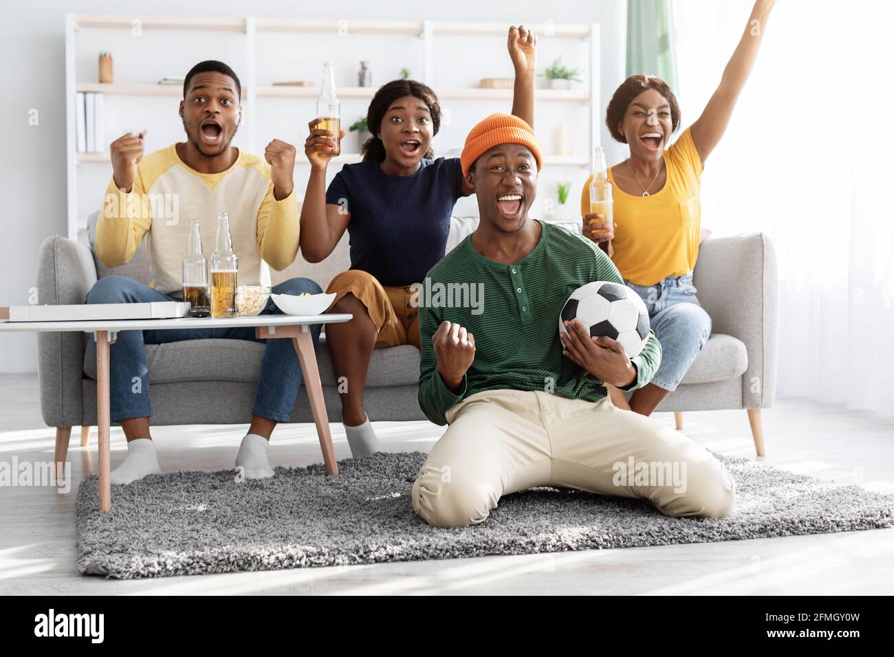 Felici amici afro-americani che guardano la partita di calcio insieme, celebrando il successo Foto Stock