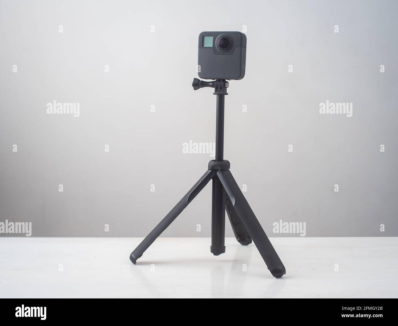 360 fotocamera su un mini treppiede con accessori contro a. Superficie bianca e grigia Foto Stock