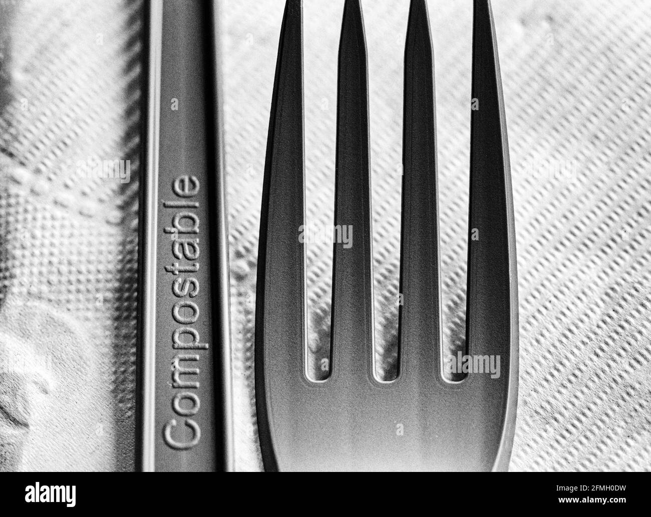 Un macro shot di una forchetta e coltello verdi e compostabili su un tovagliolo bianco crea un design astratto e suggerisce la sostenibilità nella ristorazione e nello stile di vita. Foto Stock