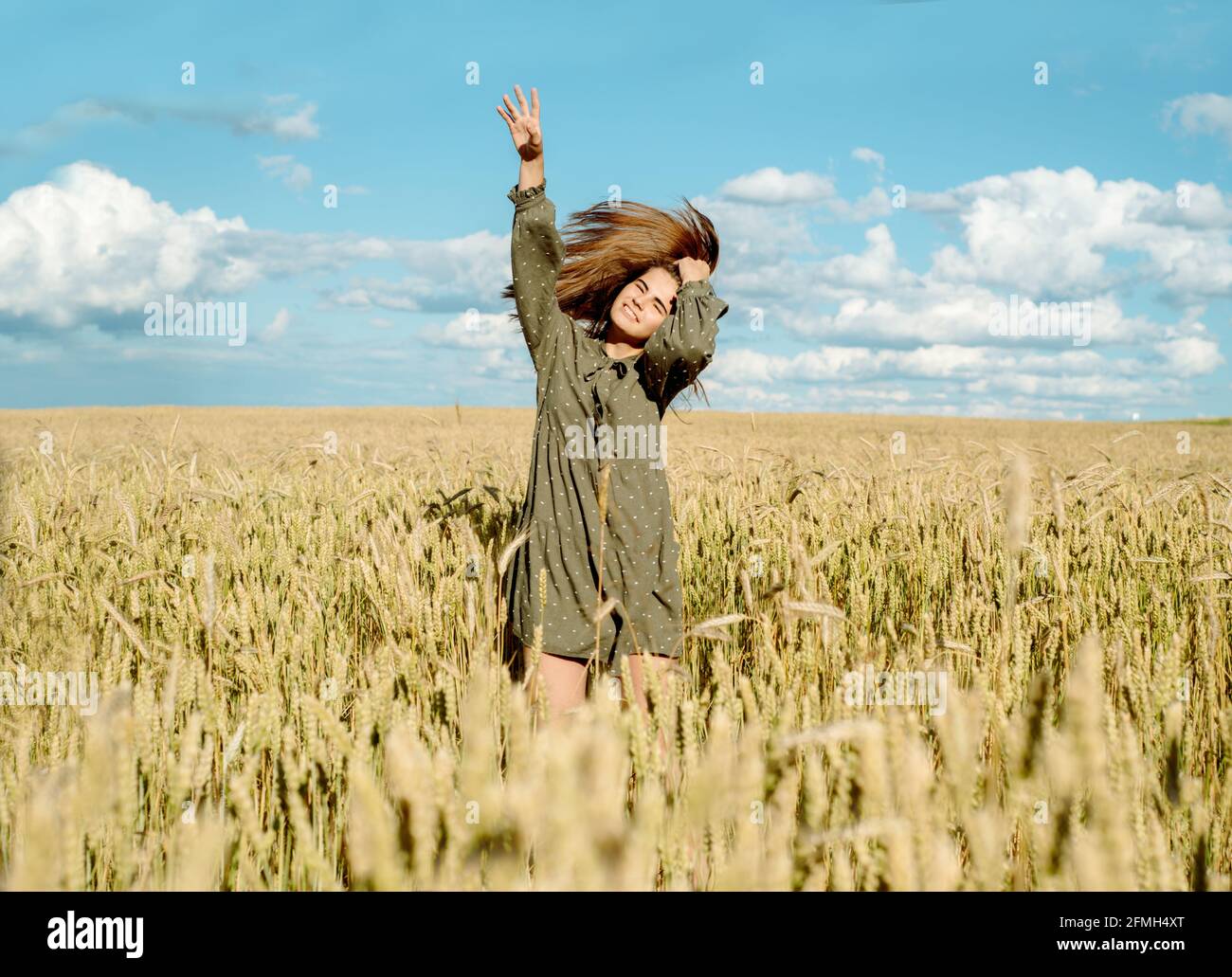 la giovane ragazza sta ballando in un campo di grano. Corre la mano sulle orecchie. Si alza con la schiena. Capelli che volano nel vento, stile di vita. Emotivamente filatura e j Foto Stock