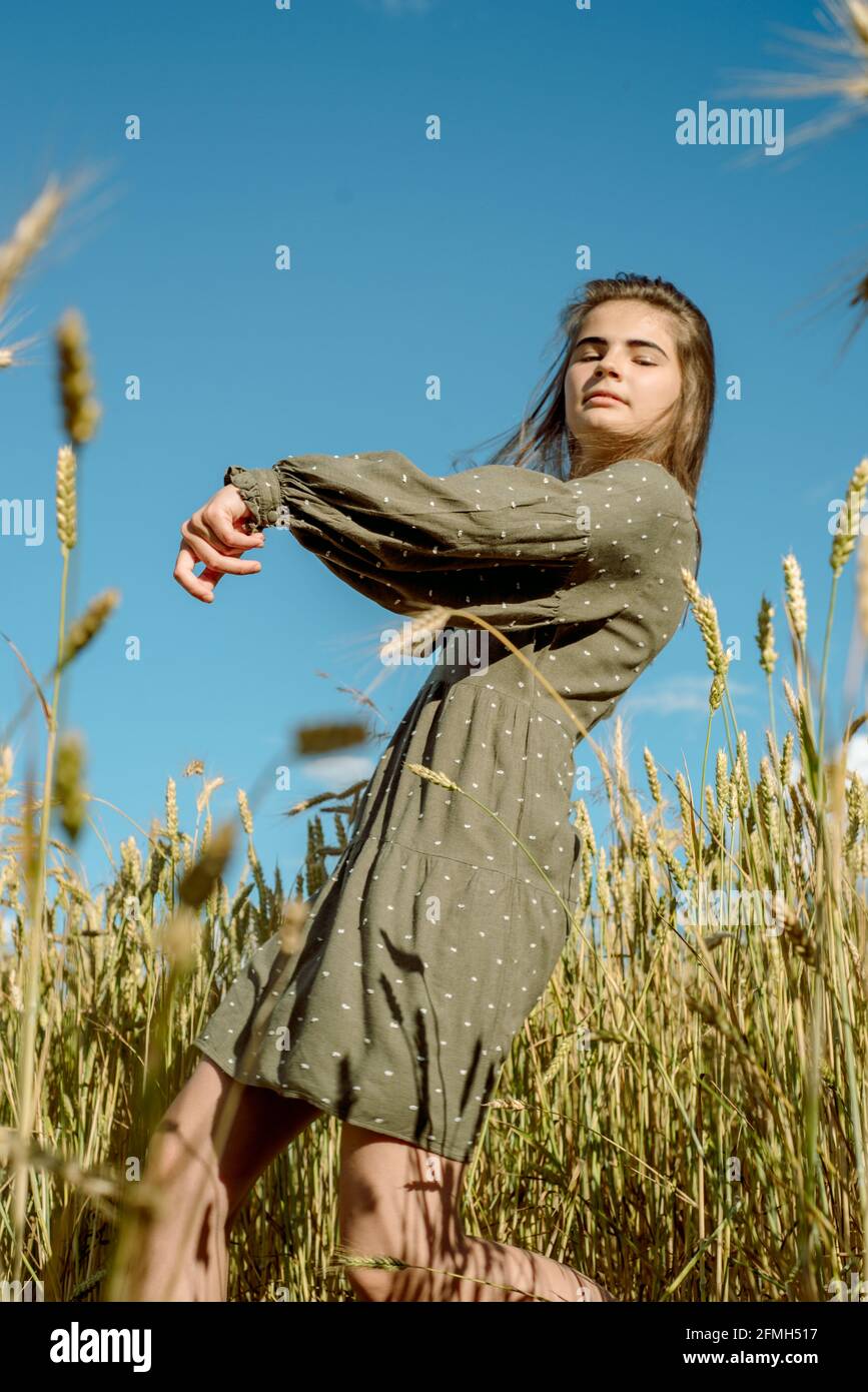 la giovane ragazza sta ballando in un campo di grano. Corre la mano sulle orecchie. Si alza con la schiena. Capelli che volano nel vento, stile di vita. Emotivamente filatura e j Foto Stock