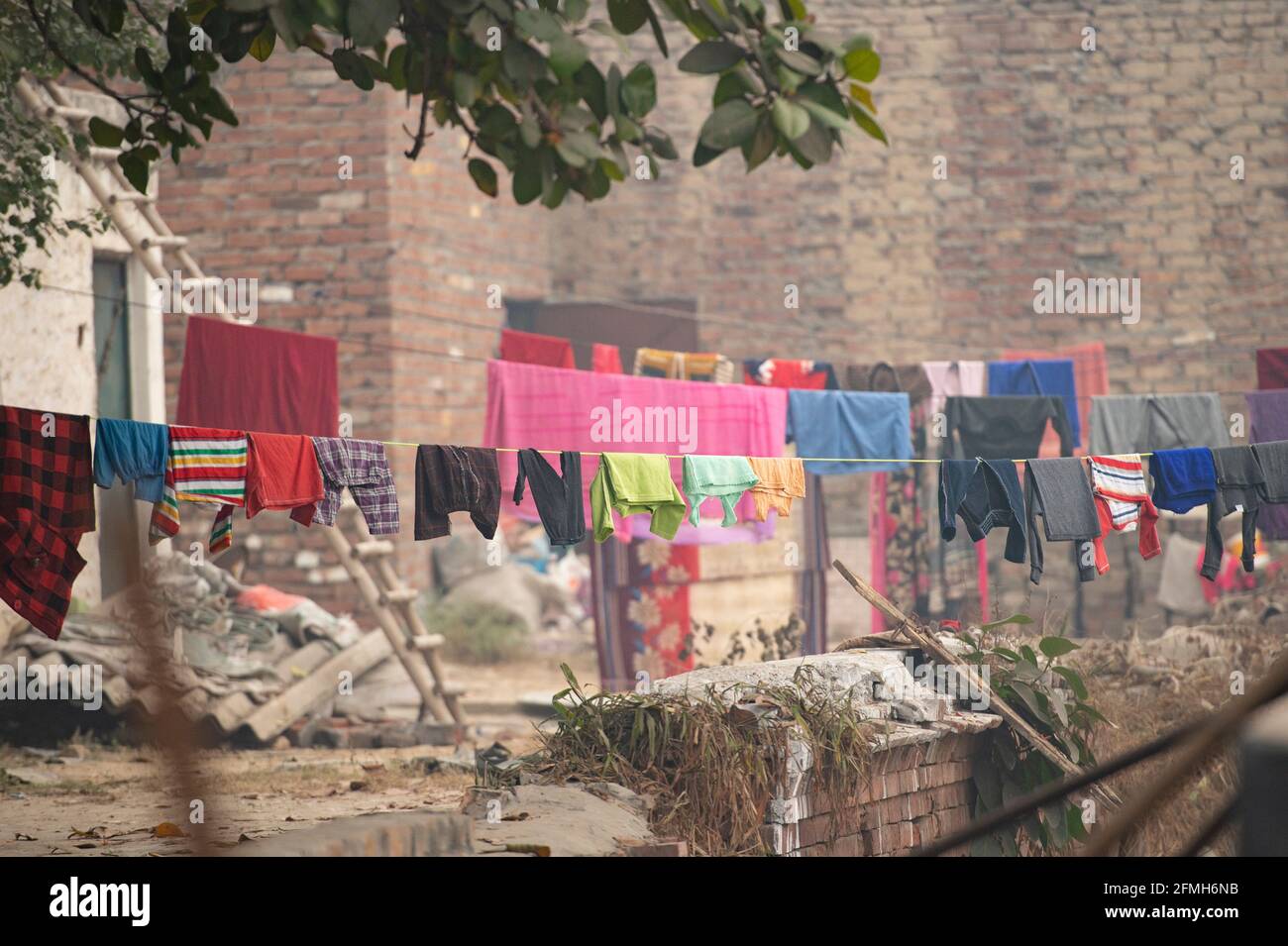 (Fuoco selettivo) alcuni vestiti colorati lavati sono appesi su una linea di vestiti o linea di lavaggio sul tetto di un edificio a Nuova Delhi, India. Foto Stock