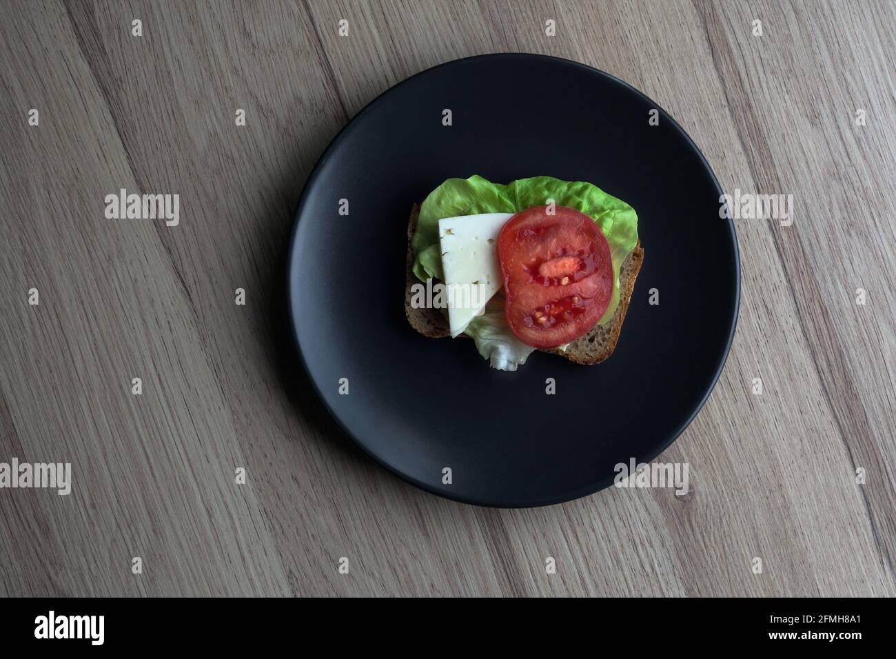 sandwich con insalata, formaggio bianco e fette di pomodoro, cibo dietetico, cibo fresco e gustoso, minimalismo Foto Stock