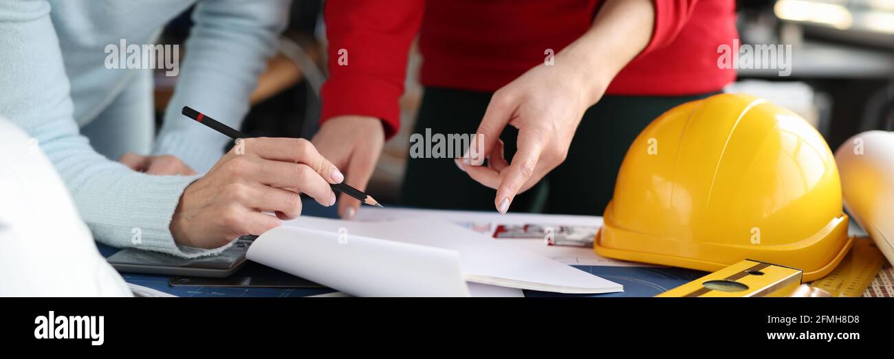 Le ingegneri femminili si riunano in ufficio e guardano al layout di appartamento in primo piano Foto Stock