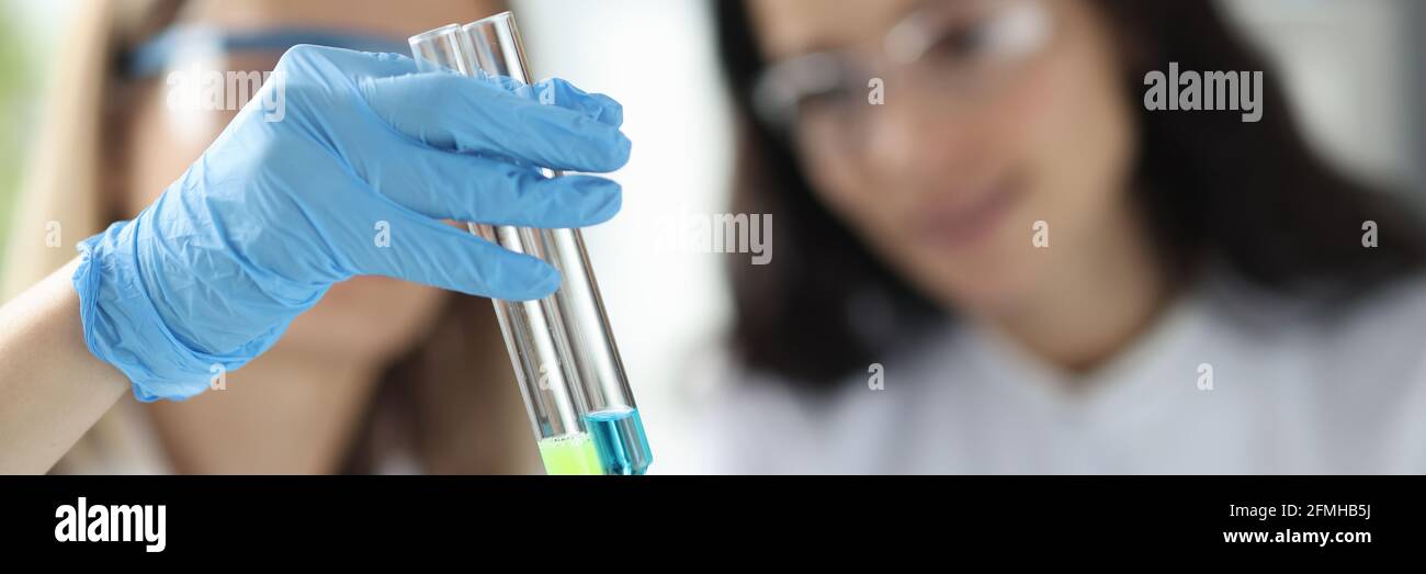 Donne scienziati che tengono provette con liquido in laboratorio Foto Stock