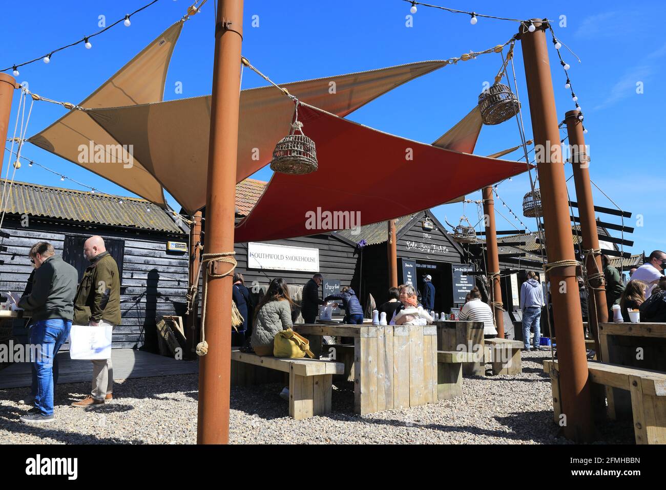 Persone che mangiano al Sole Bay Fish Company, al sole di primavera sulla costa sud-occidentale, a Suffolk, Regno Unito Foto Stock