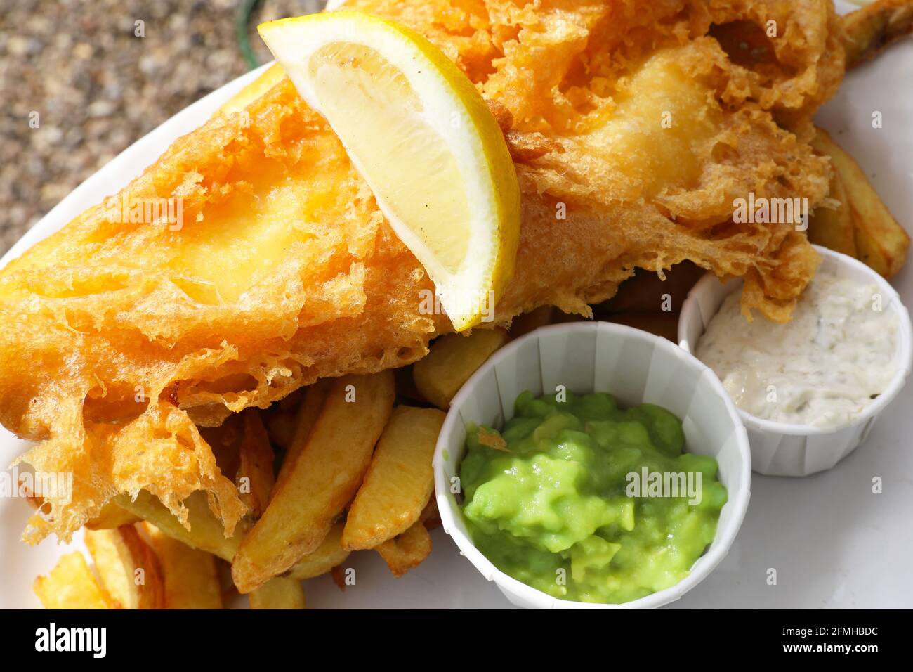 Pesce e patatine, con lato di piselli e salsa tartare, serviti all'aperto in un pub Suffolk, East Anglia, Regno Unito Foto Stock