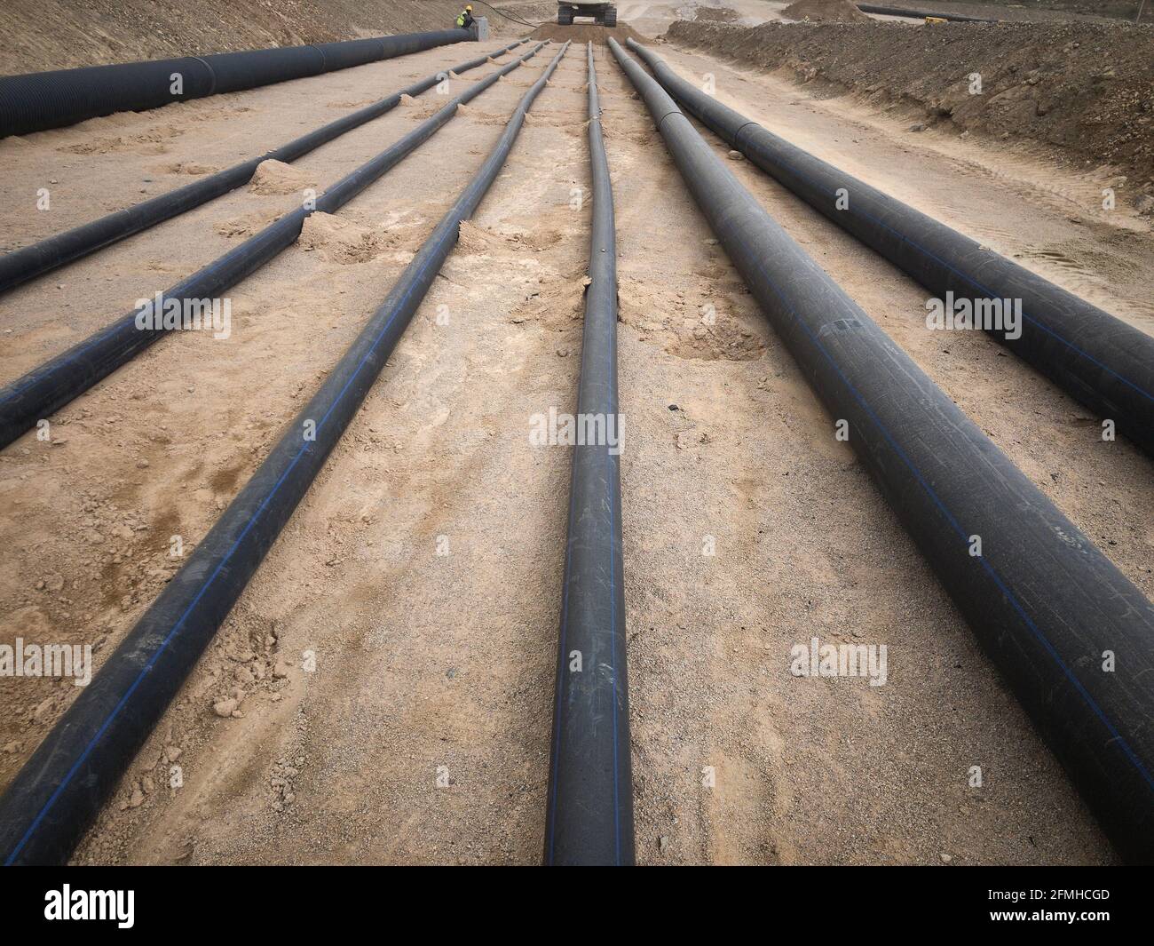 Tubi dell'acqua di plastica neri posati su fondamenta di sabbia Foto Stock