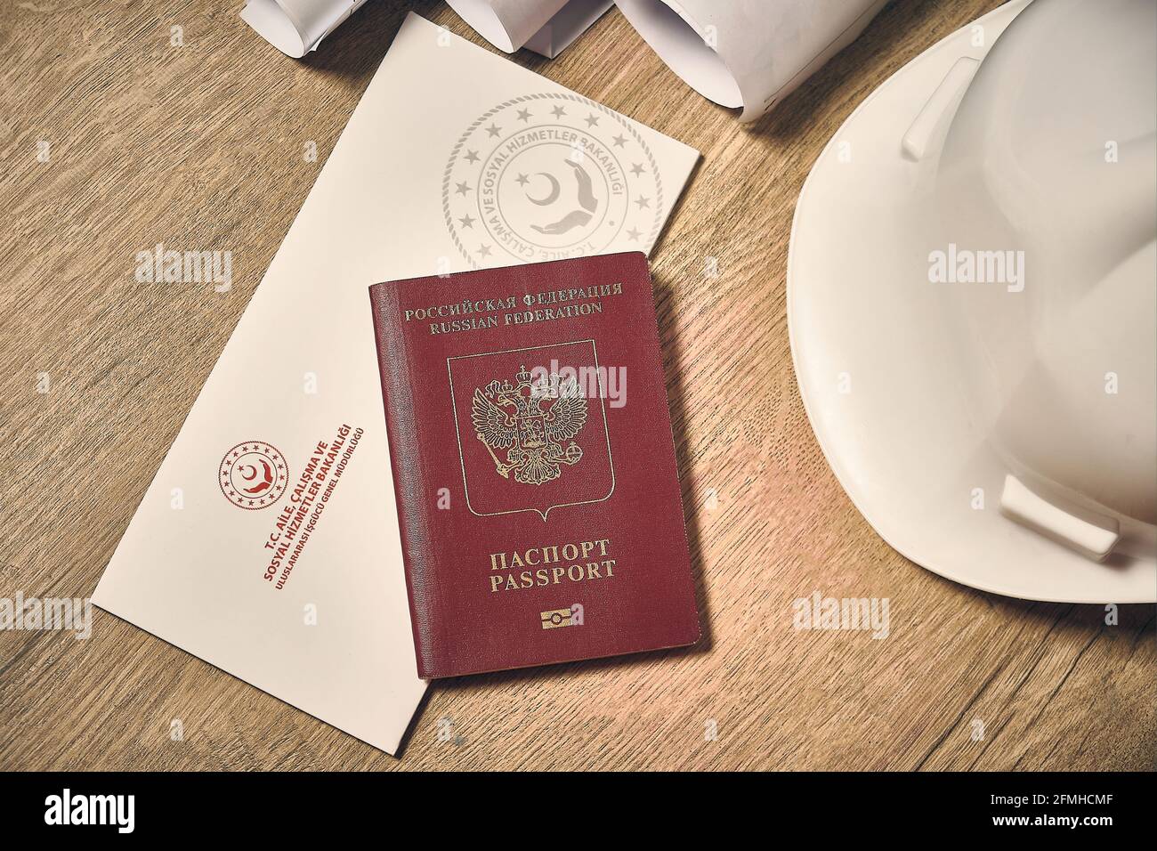Cappello bianco, passaporto straniero russo e permesso di lavoro turco presso la scrivania in legno vista dall'alto verso il basso Foto Stock