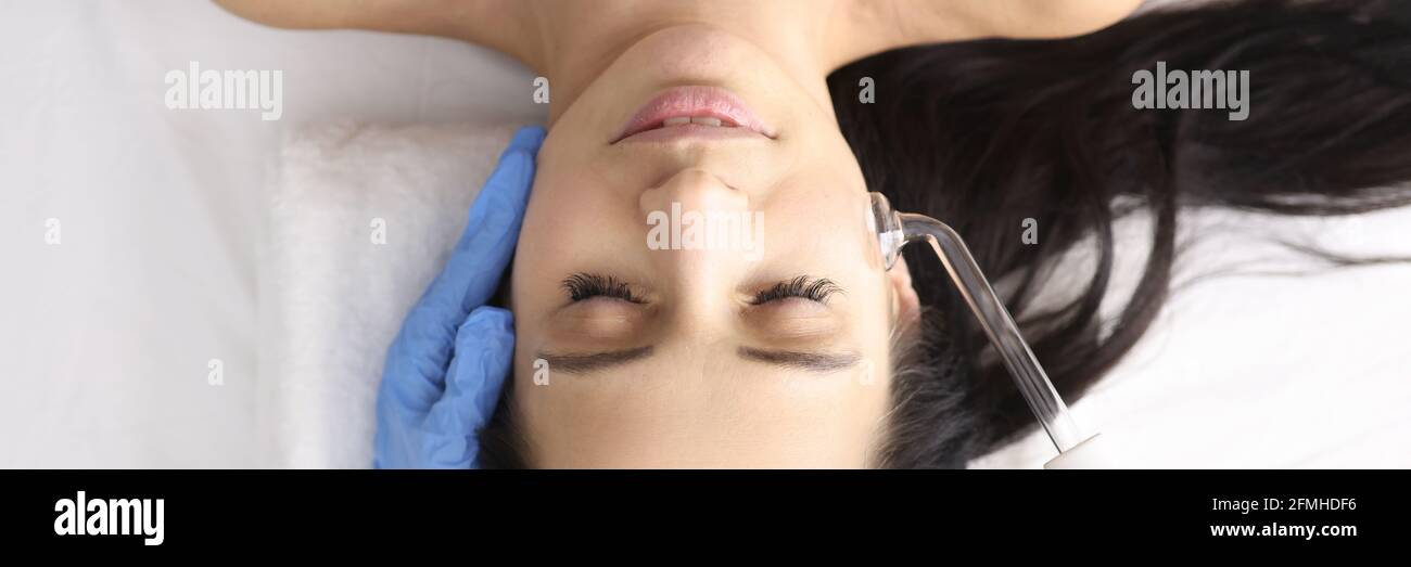 Dottore in guanti facendo massaggio viso con darsonval Foto Stock