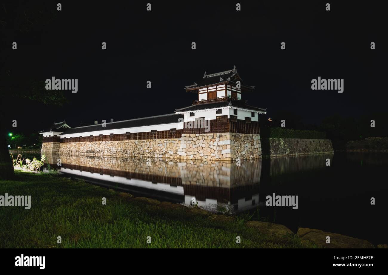 Le mura fortezze illuminate del castello di Hiroshima, chiamato anche Castello di Carp, circondato da acqua con riflessi di notte, Hiroshima, Giappone Foto Stock