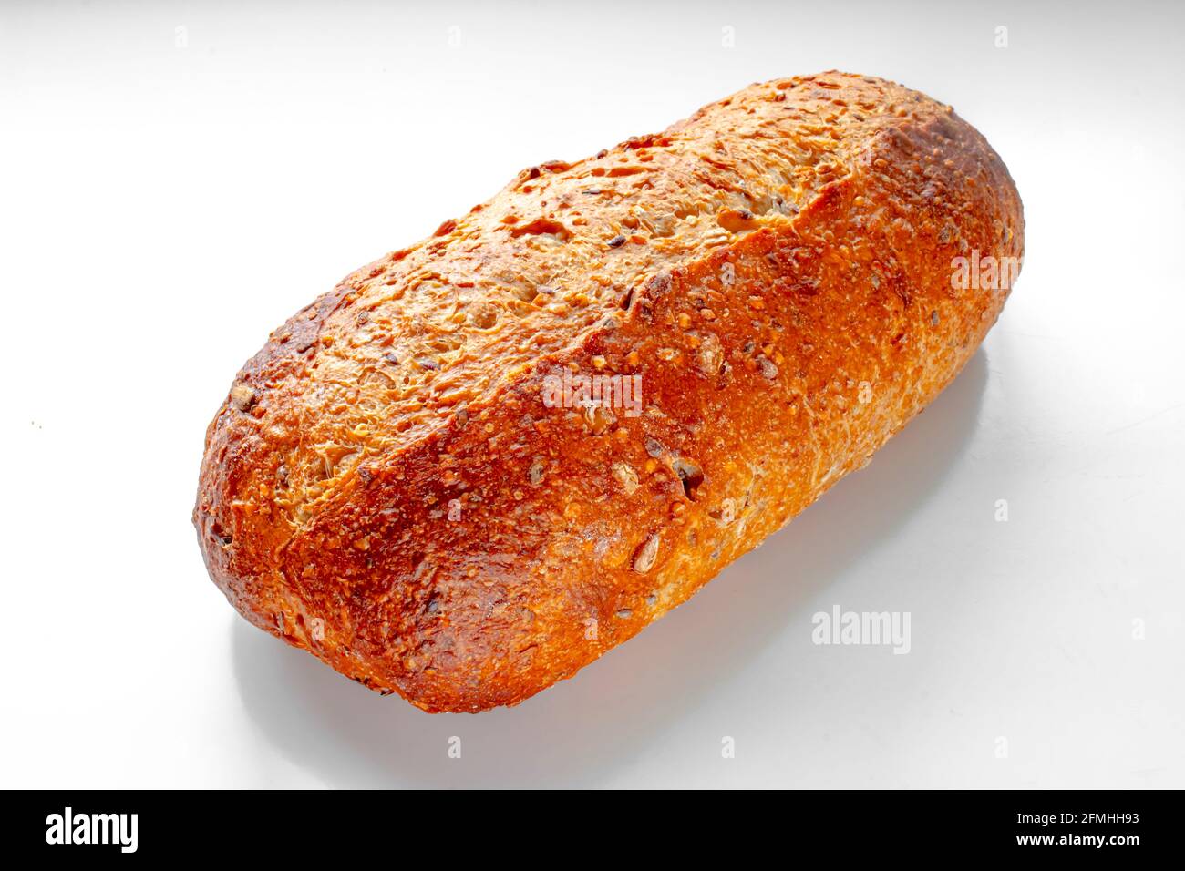 Vista frontale di un panino artigianale da forno, ovale di grano raccolto su un tavolo bianco. Foto Stock