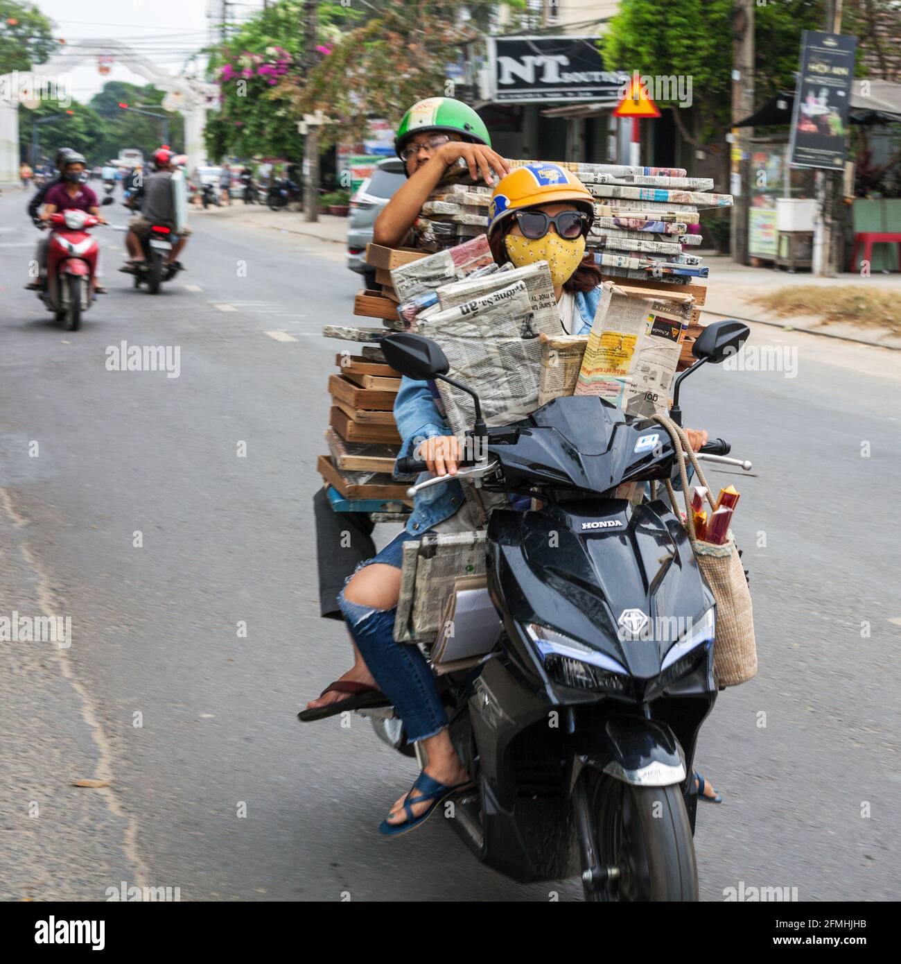 Coppia vietnamita su scooter non sicuro e carico pesante che trasporta pallet di legno, Hoi An, Vietnam Foto Stock