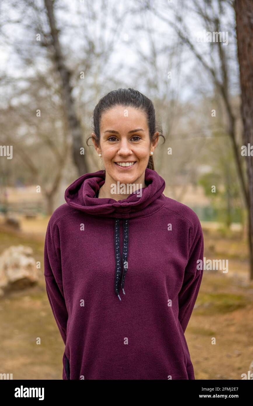 Contenuto per adulti femminile in morbido abbigliamento guardando la fotocamera con sorrisi su sfondo sfocato Foto Stock