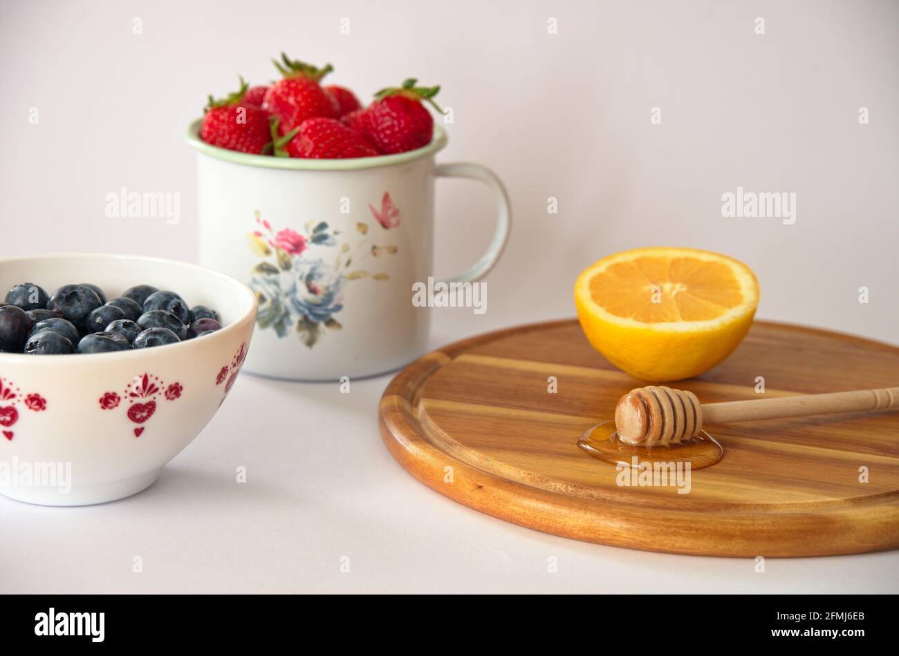 Frutti di bacche sani con miele e limone su sfondo bianco Foto Stock