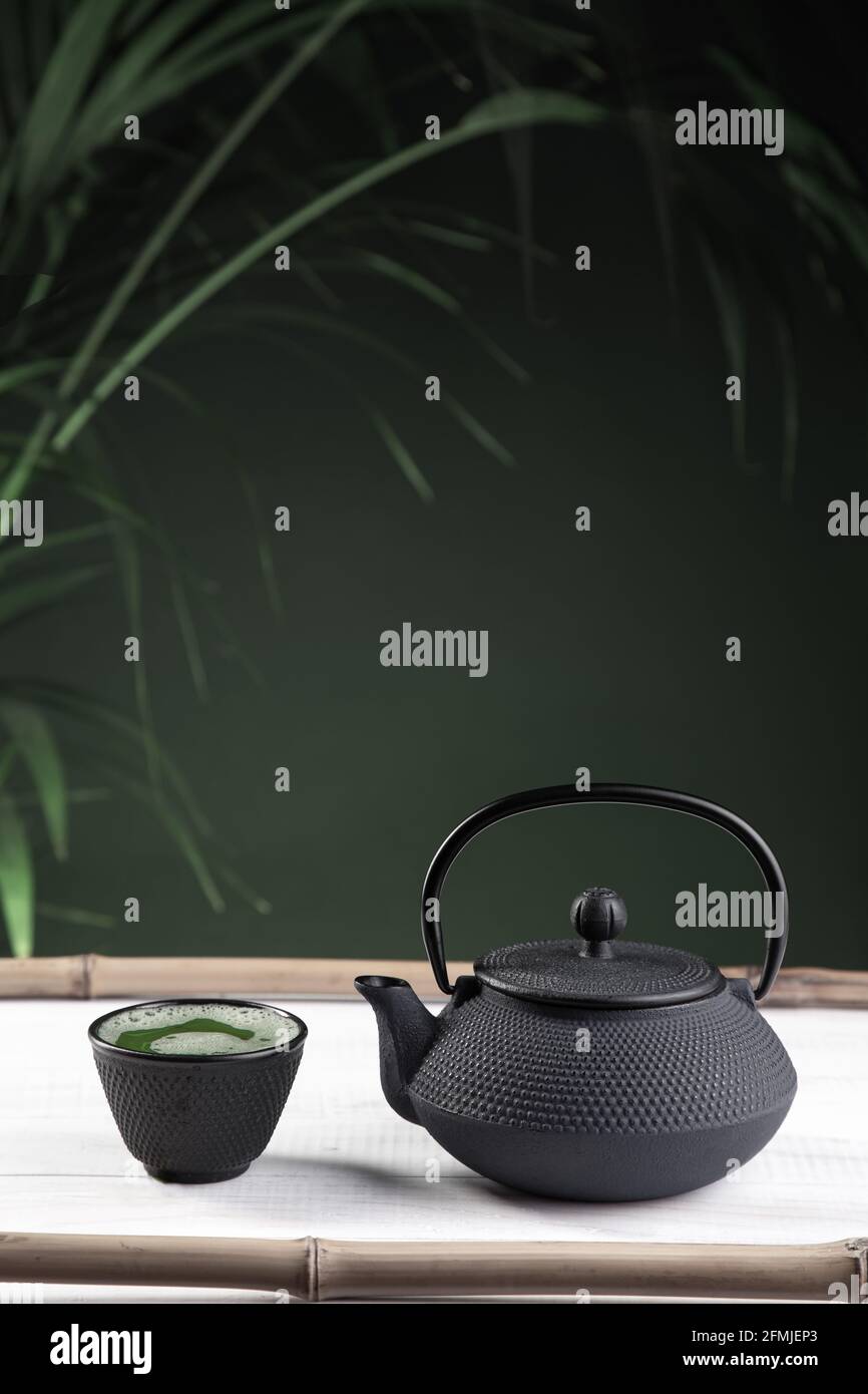 Tè Matcha e teiera su sfondo verde su base di legno bianco. Bevanda tradizionale Giapponese. Formato verticale. Foto Stock