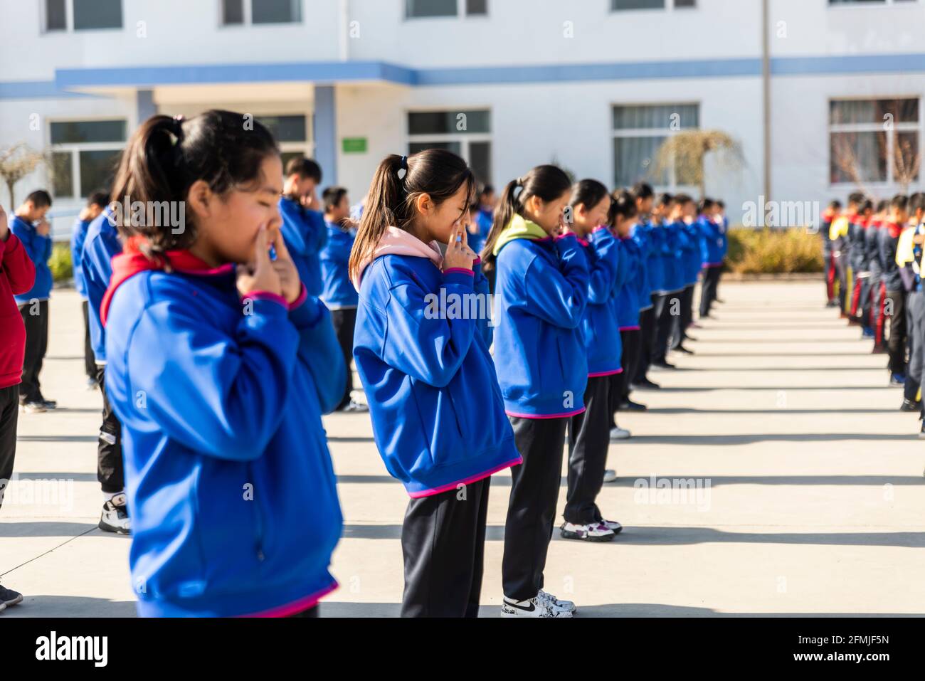 Gli studenti junior della scuola BoAi fanno il loro esercizio visivo mattutino giornaliero. Foto Stock