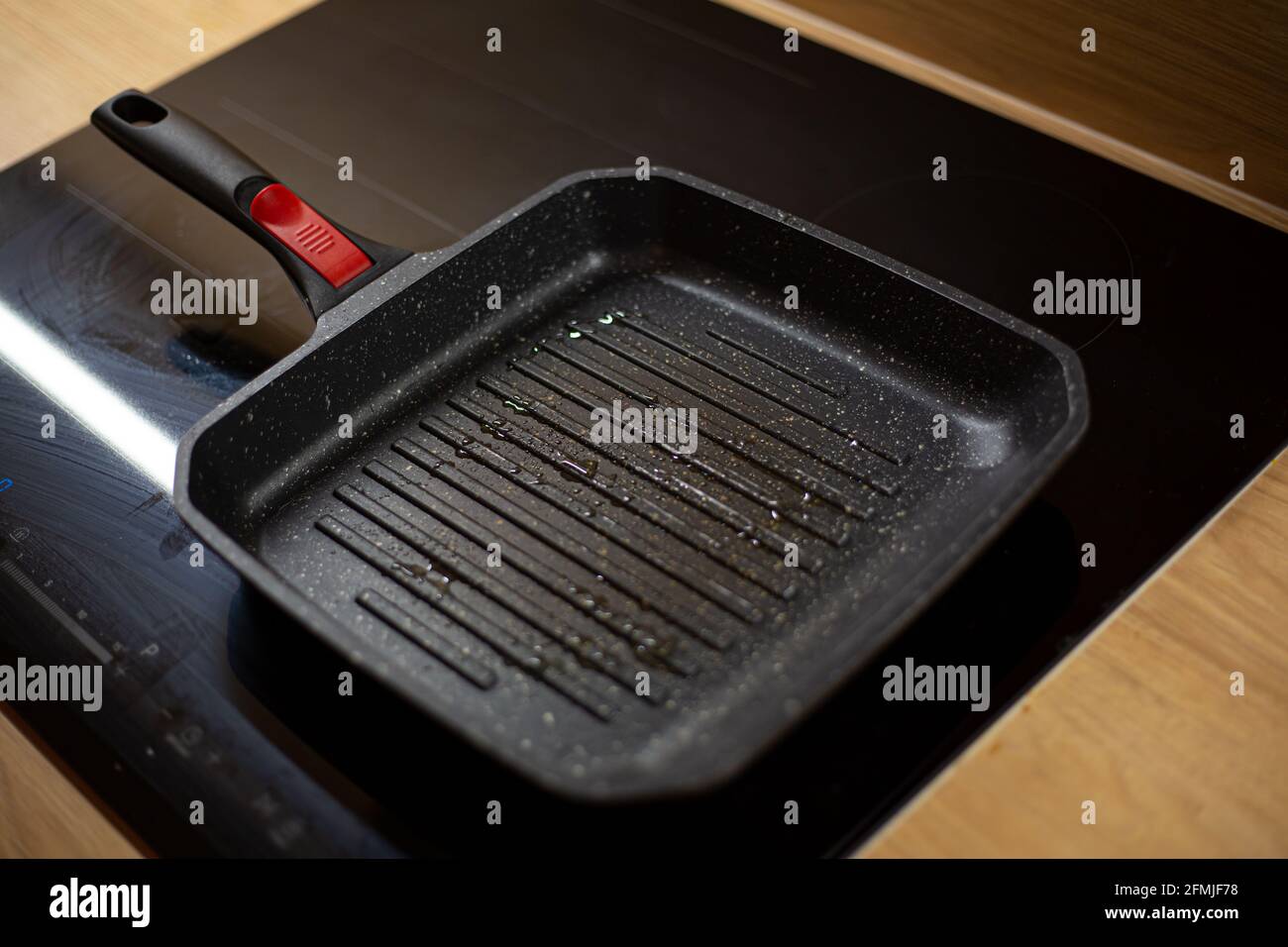 La teglia nera per grigliate oleosa si sta riscaldando su un piano cottura elettrico in ceramica per la cottura degli hamburger a casa. Foto Stock