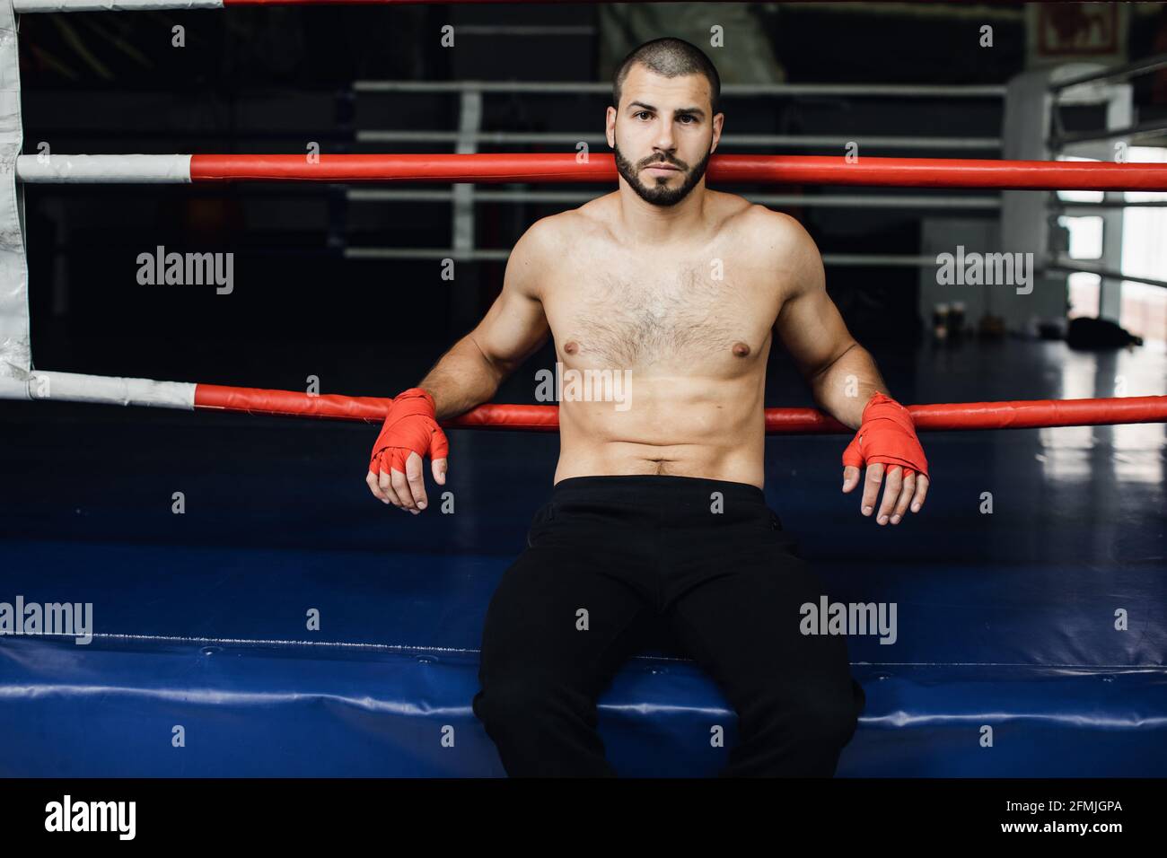 Combattente che pratica alcuni calci con la sacca di punzonatura. Calcio, sacchetto di punzonatura su sfondo scuro. Il sacchetto nero per punzonatura pesa in palestra Foto Stock