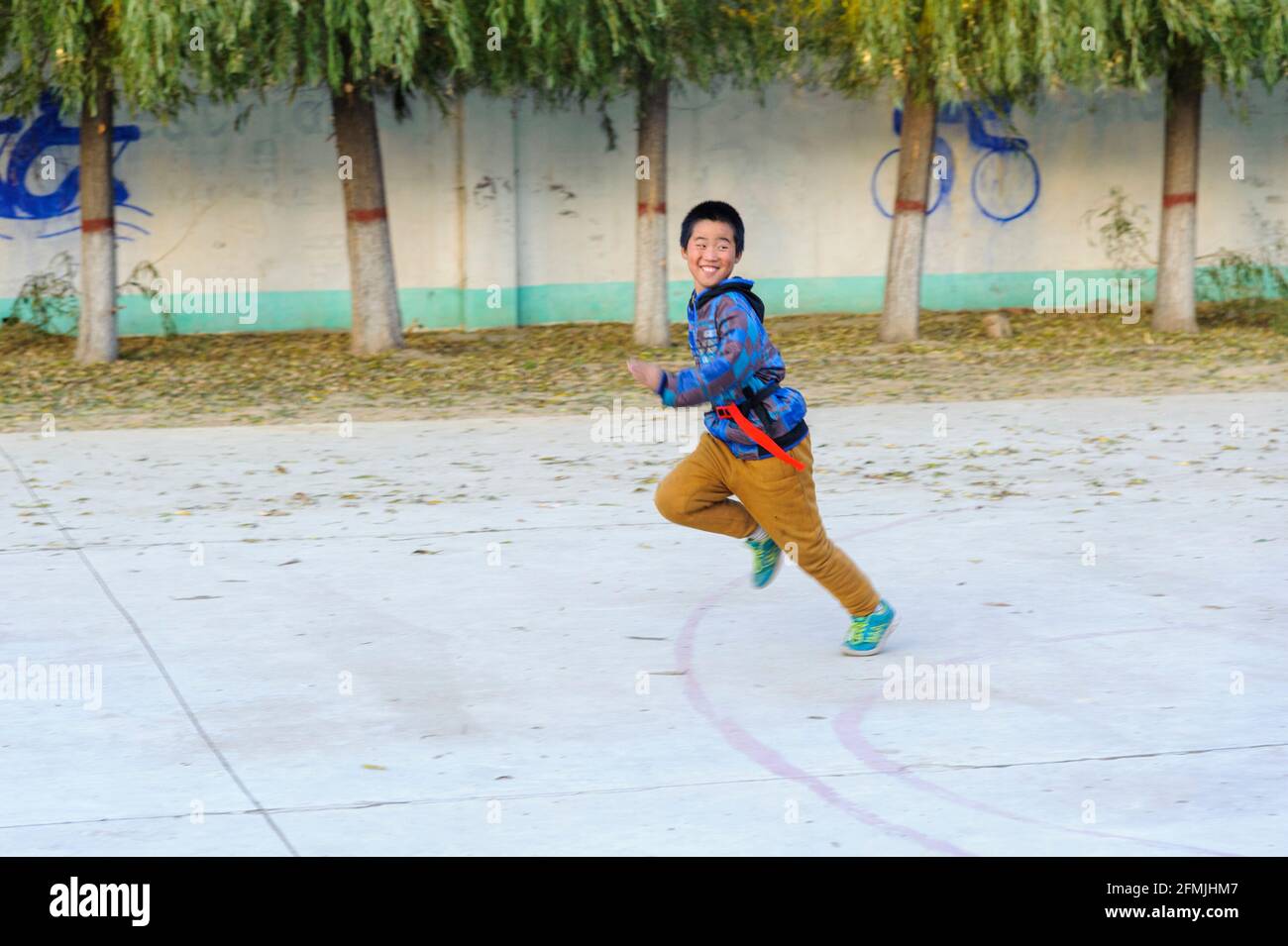 Gli studenti della scuola lixiana nelle zone rurali di Hebei, in Cina, scappare durante il gioco cattura la bandiera. Foto Stock