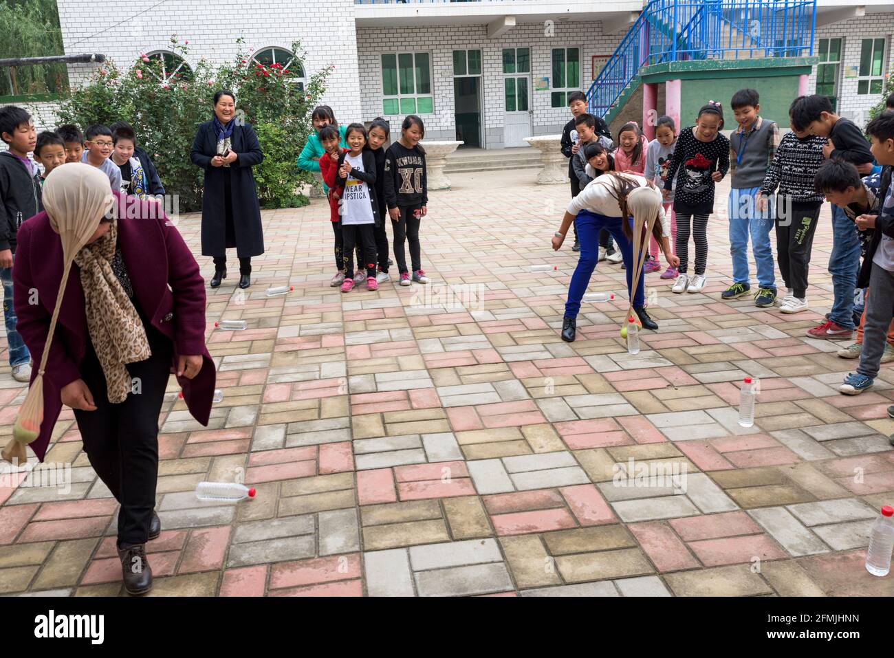 Insegnanti e studenti della scuola Lixiana di Hebei partecipano alla gara di relè per abbattere le bottiglie d'acqua con il pantyhose sulla testa. Foto Stock