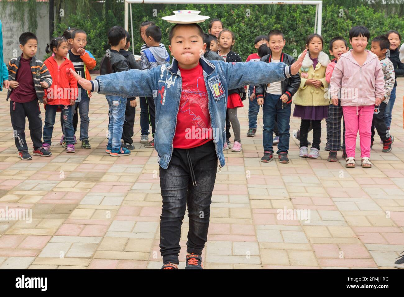Gli studenti della scuola Lixiana di Hebei, in Cina, bilanciano un piatto e una ciotola mentre camminano verso il traguardo di una gara di relè. Foto Stock