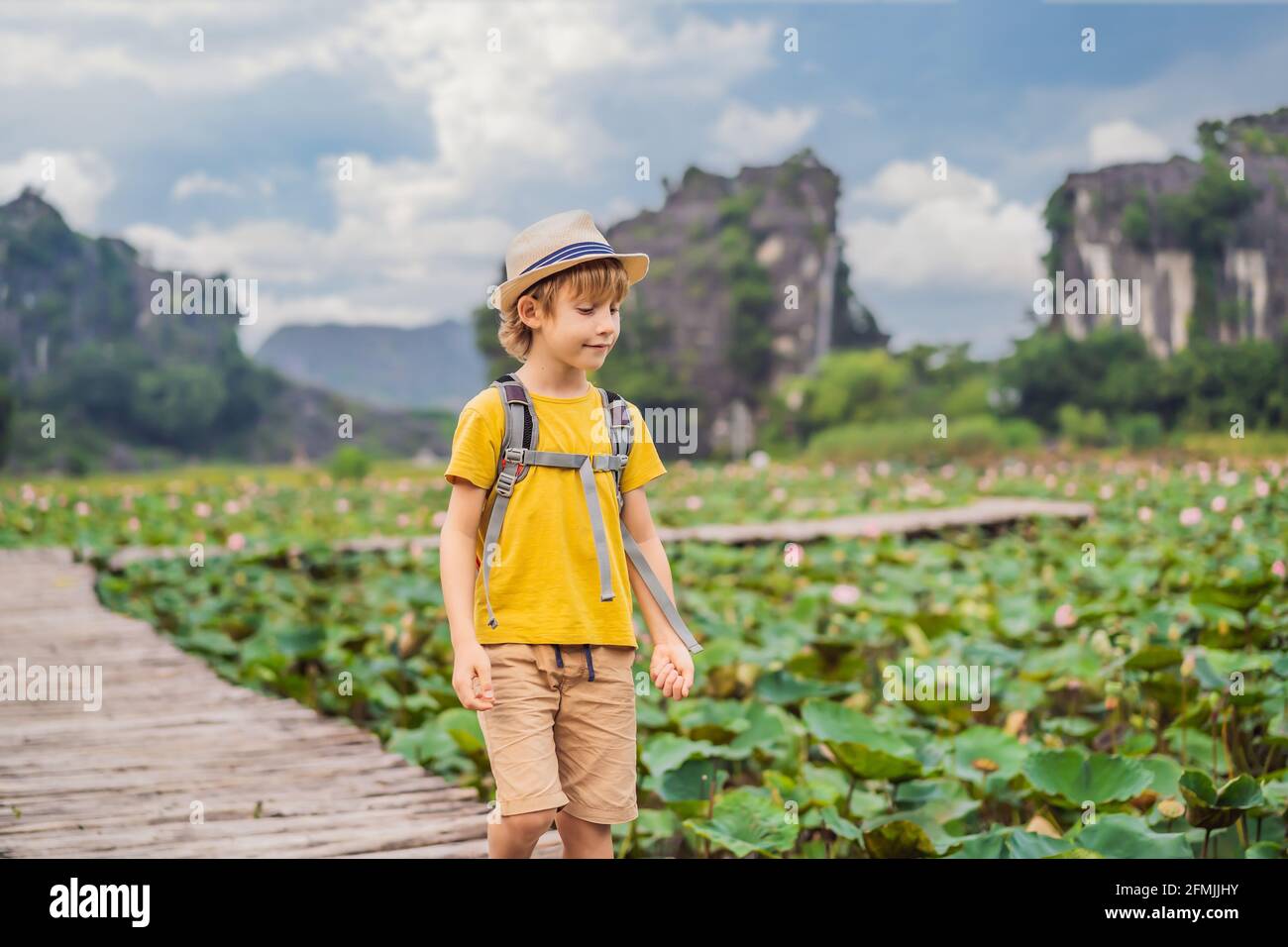 Ragazzo in un giallo sul sentiero tra il lago di loto. MUA Cave, Ninh Binh, Vietnam. Il Vietnam riapre dopo la quarantena Coronovirus COVID 19 Concept Foto Stock