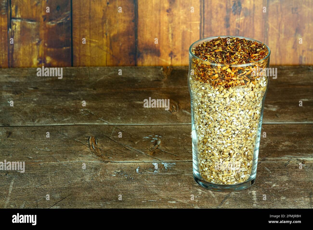 Vetro di pinta riempito con malto d'orzo gli ingredienti crudi utilizzati per fare birre chiare artigianali Foto Stock