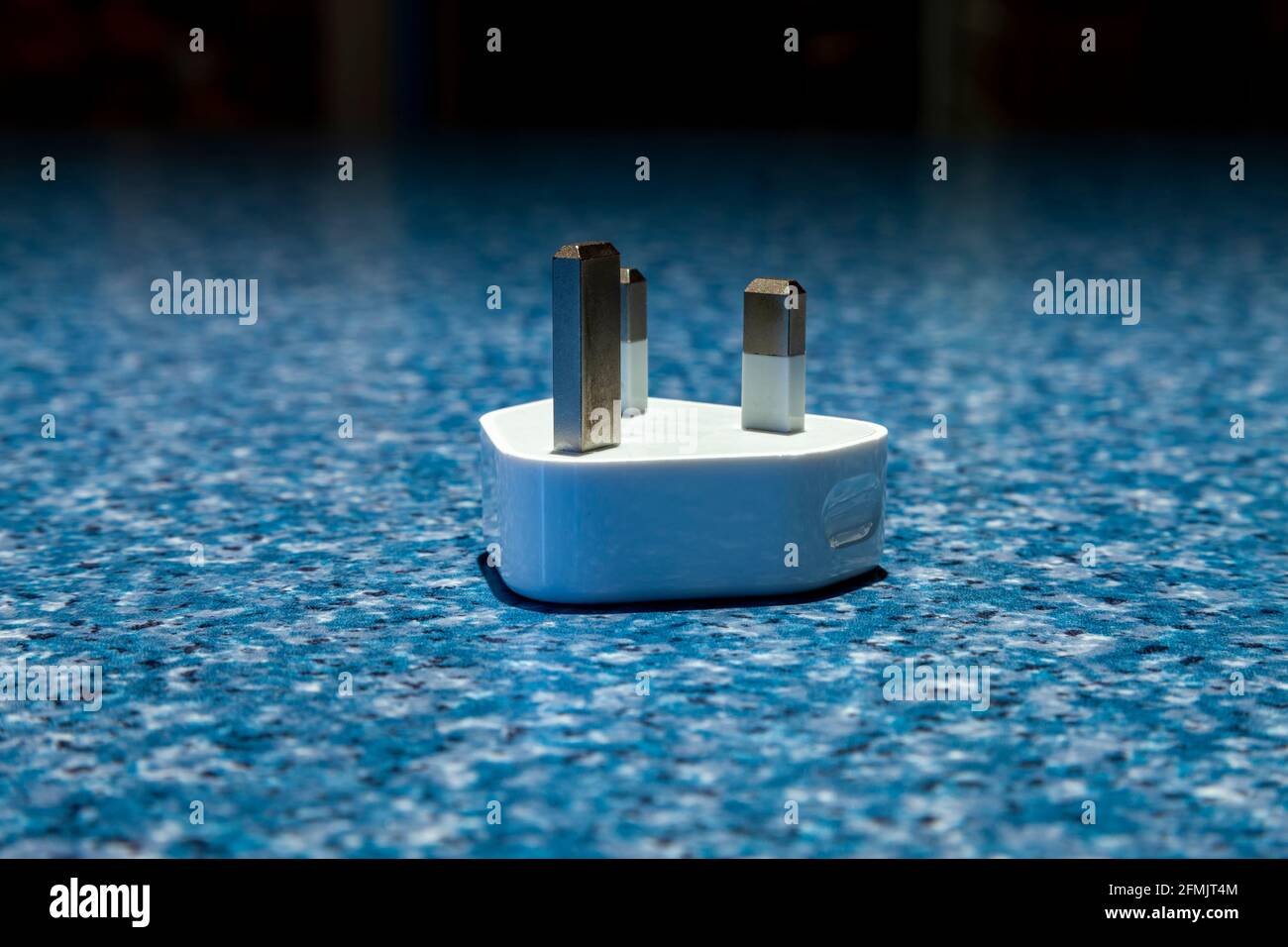 Una spina a 3 pin sul retro con un connettore usb per ricaricare i telefoni su una superficie blu a chiazze. Northampton, Inghilterra, Regno Unito. Foto Stock