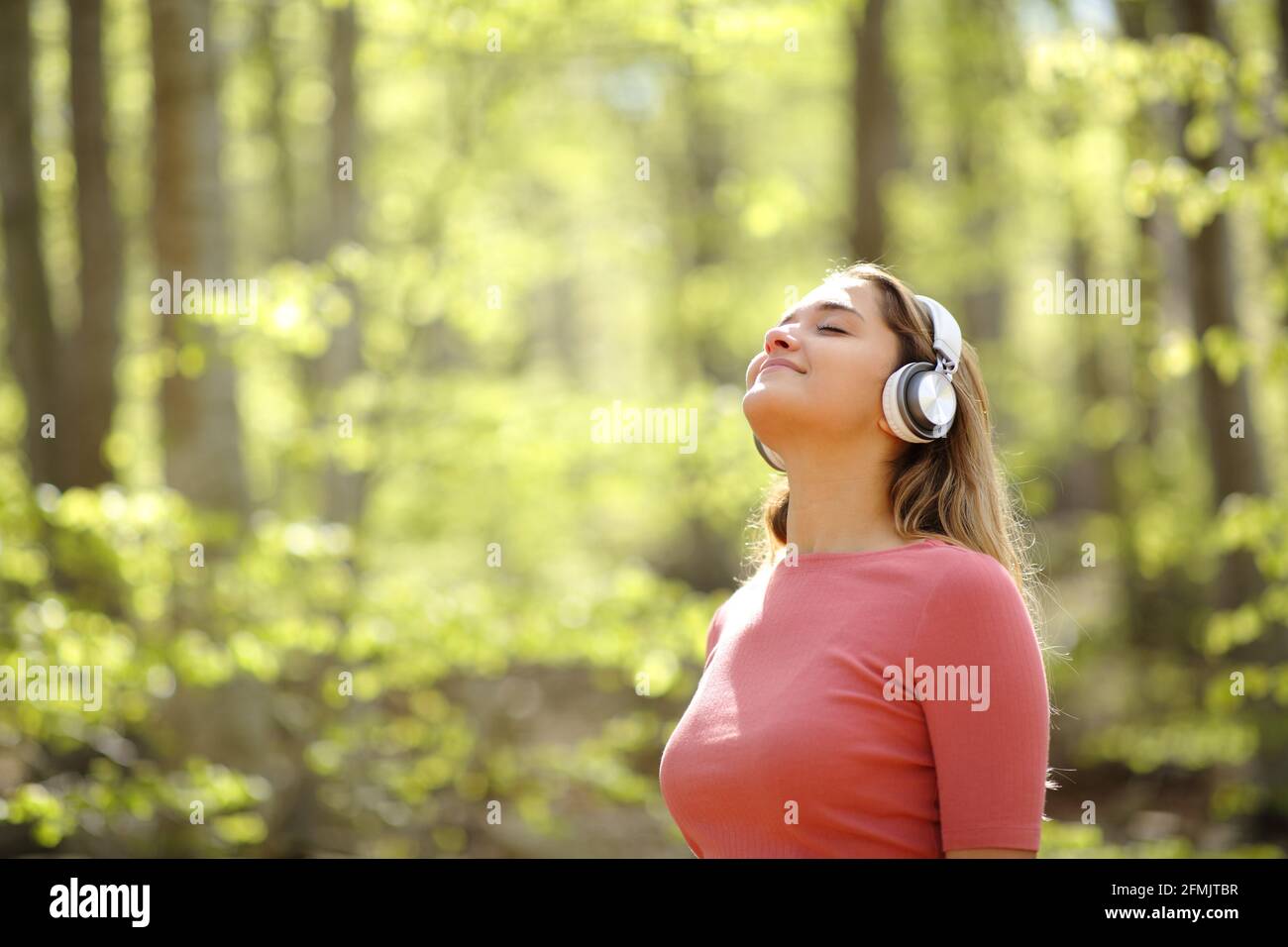 Donna che medita indossando le cuffie ascoltando l'audioguida in una foresta Foto Stock