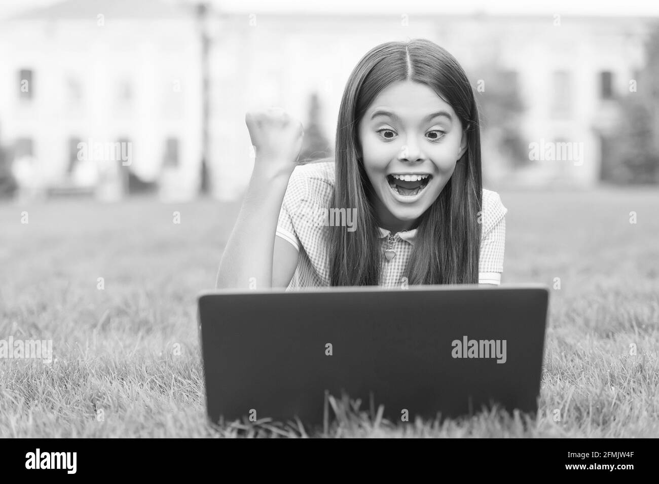 Negozio online. Blogging felice. Ragazza seduta su erba verde con laptop. Avvio. Bambino che gioca al computer. Torna a scuola. Formazione online Foto Stock