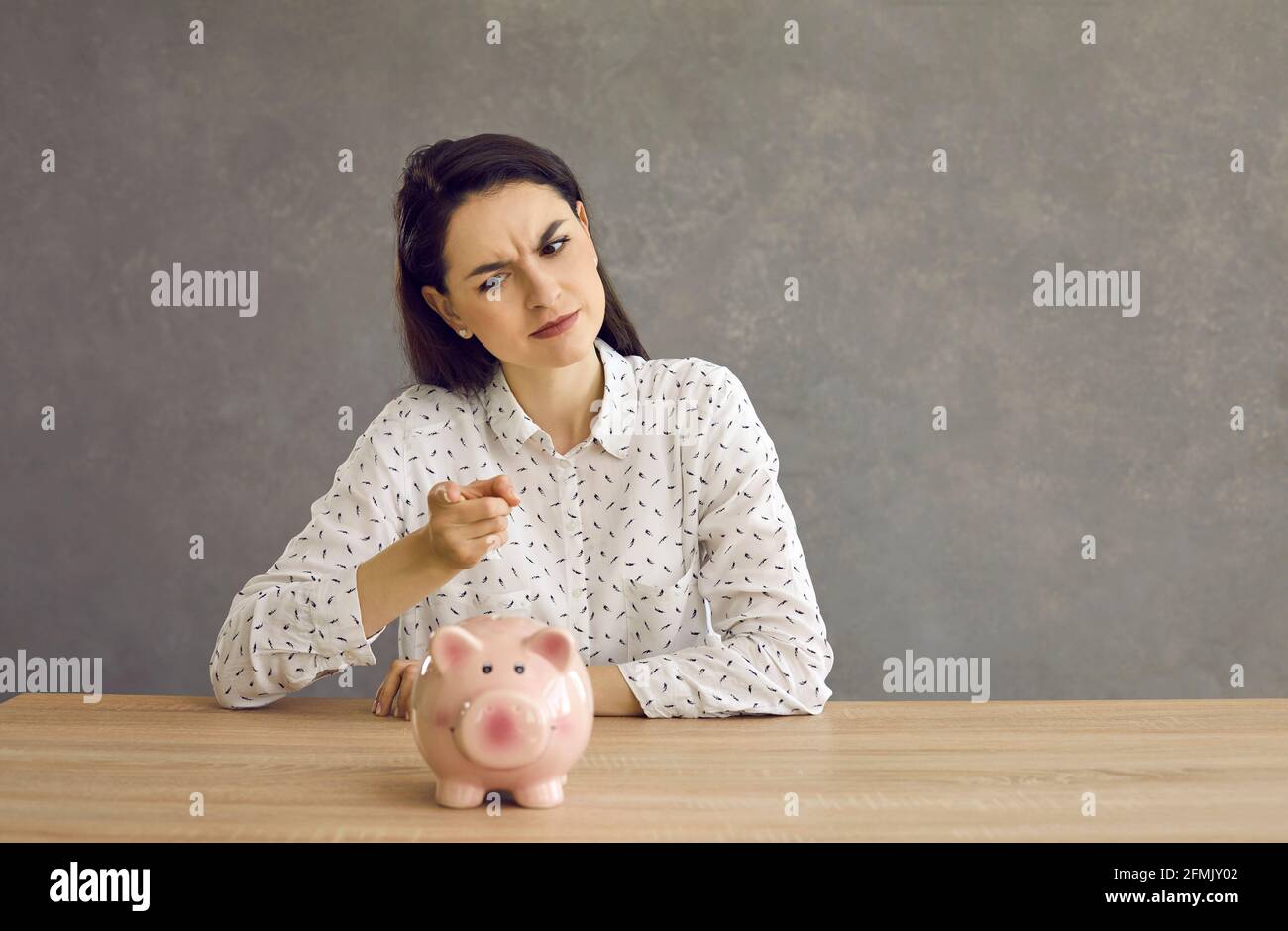 La donna ondeggia un dito punitivo contro la banca piggy come un segno che ora sarà più frugale. Foto Stock