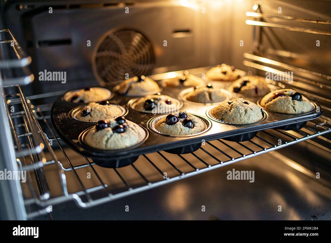 muffin mentre si cuoce nel forno con mirtilli e retroilluminazione Foto Stock