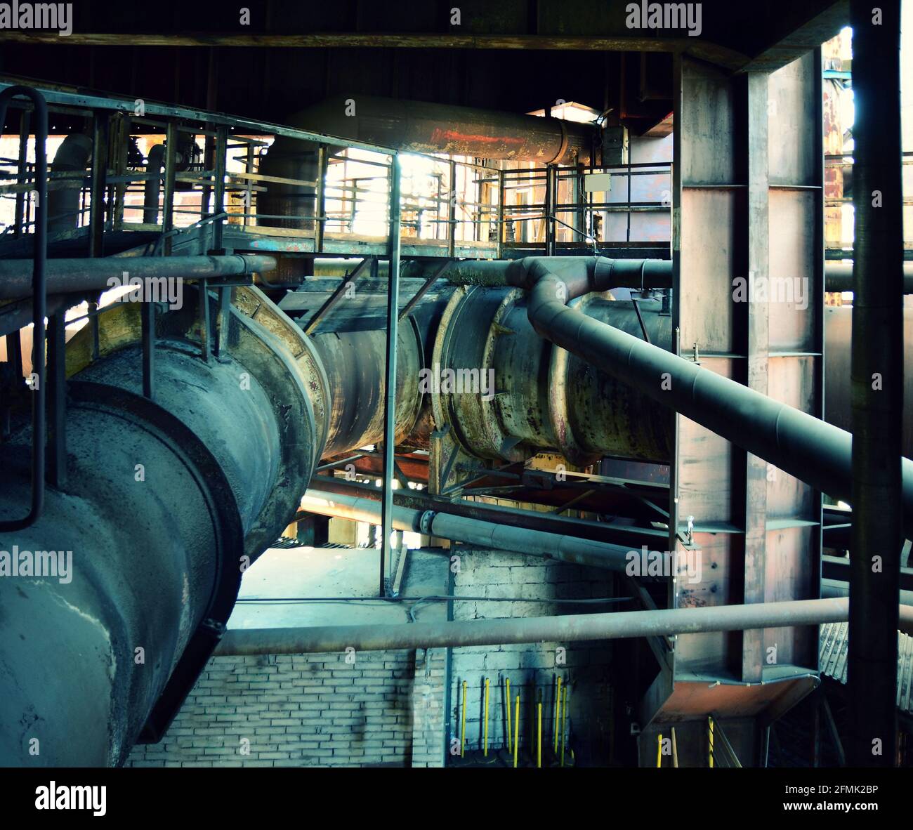 Vecchi interni di fabbrica abbandonati con molte tubazioni arrugginite. Grandi tubazioni arrugginite in fabbrica. Foto Stock