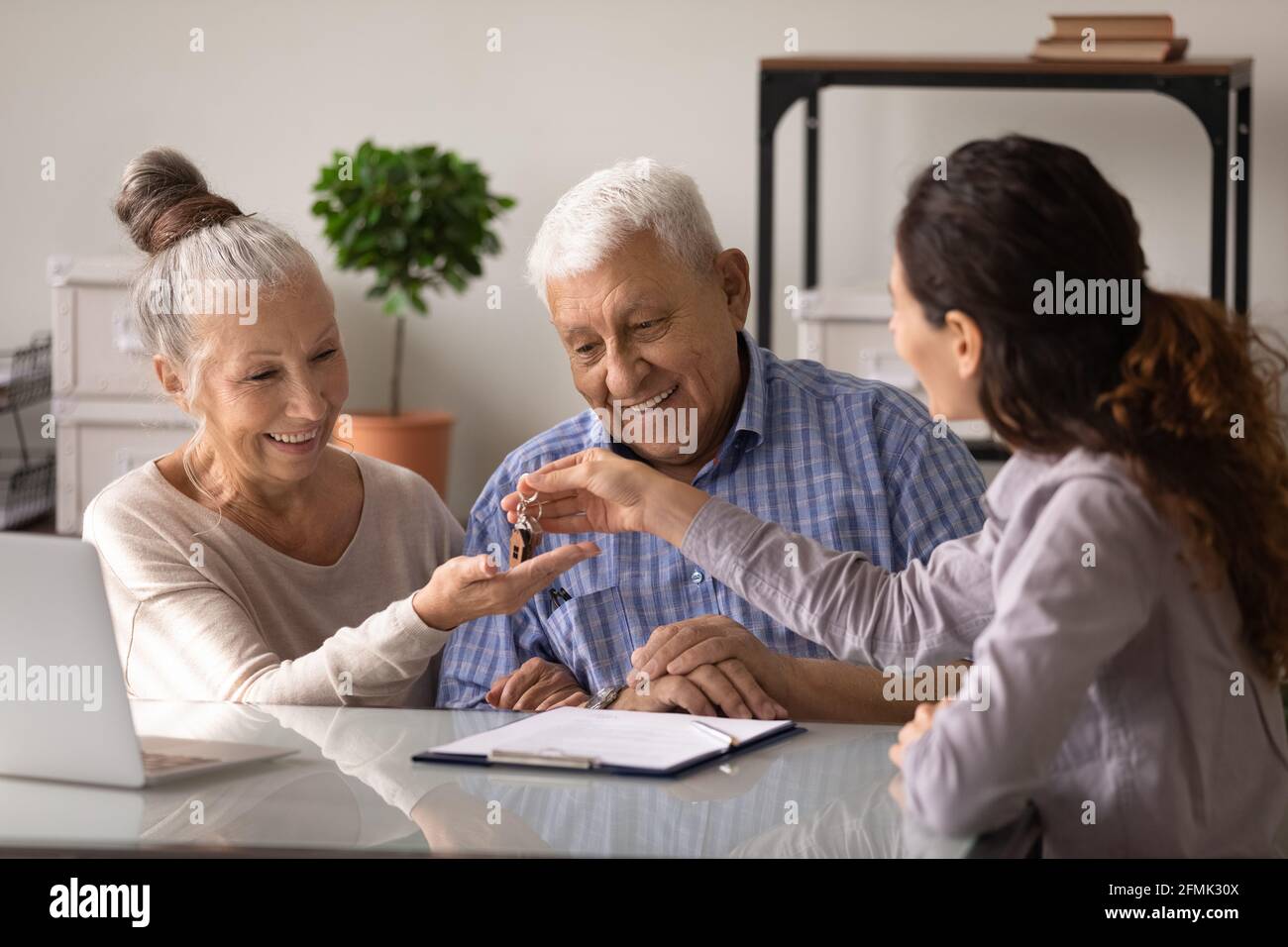 I coniugi senior più accaniti gli acquirenti di realty ricevono le chiavi nell'ufficio del realtor Foto Stock