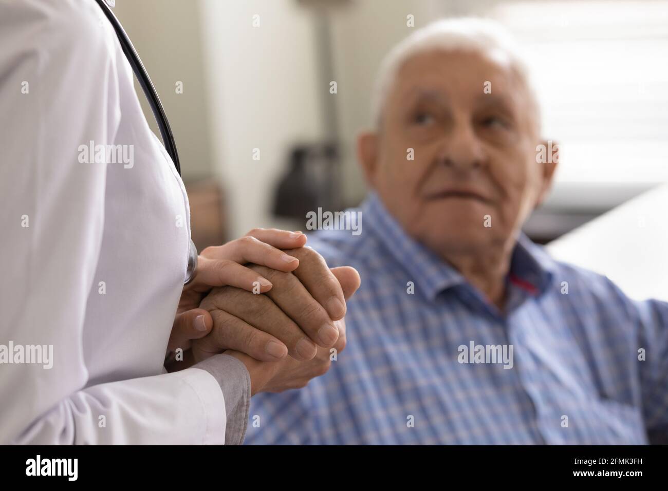 Infermiera medica femminile compassionevole che sostiene il consoling paziente anziano dell'uomo in pensione Foto Stock