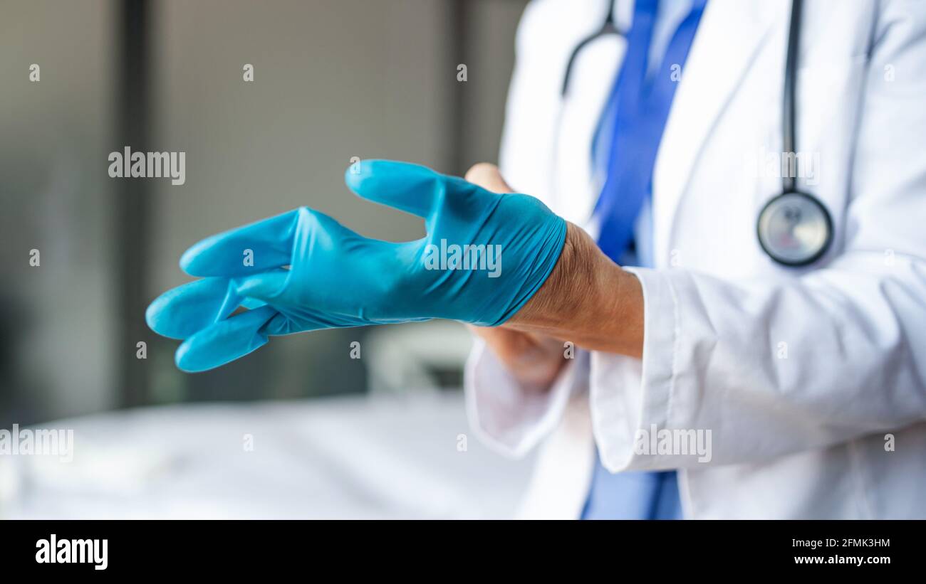 Irriconoscibile medico di donna anziana che mette sui guanti in ospedale, concetto di coronavirus. Foto Stock