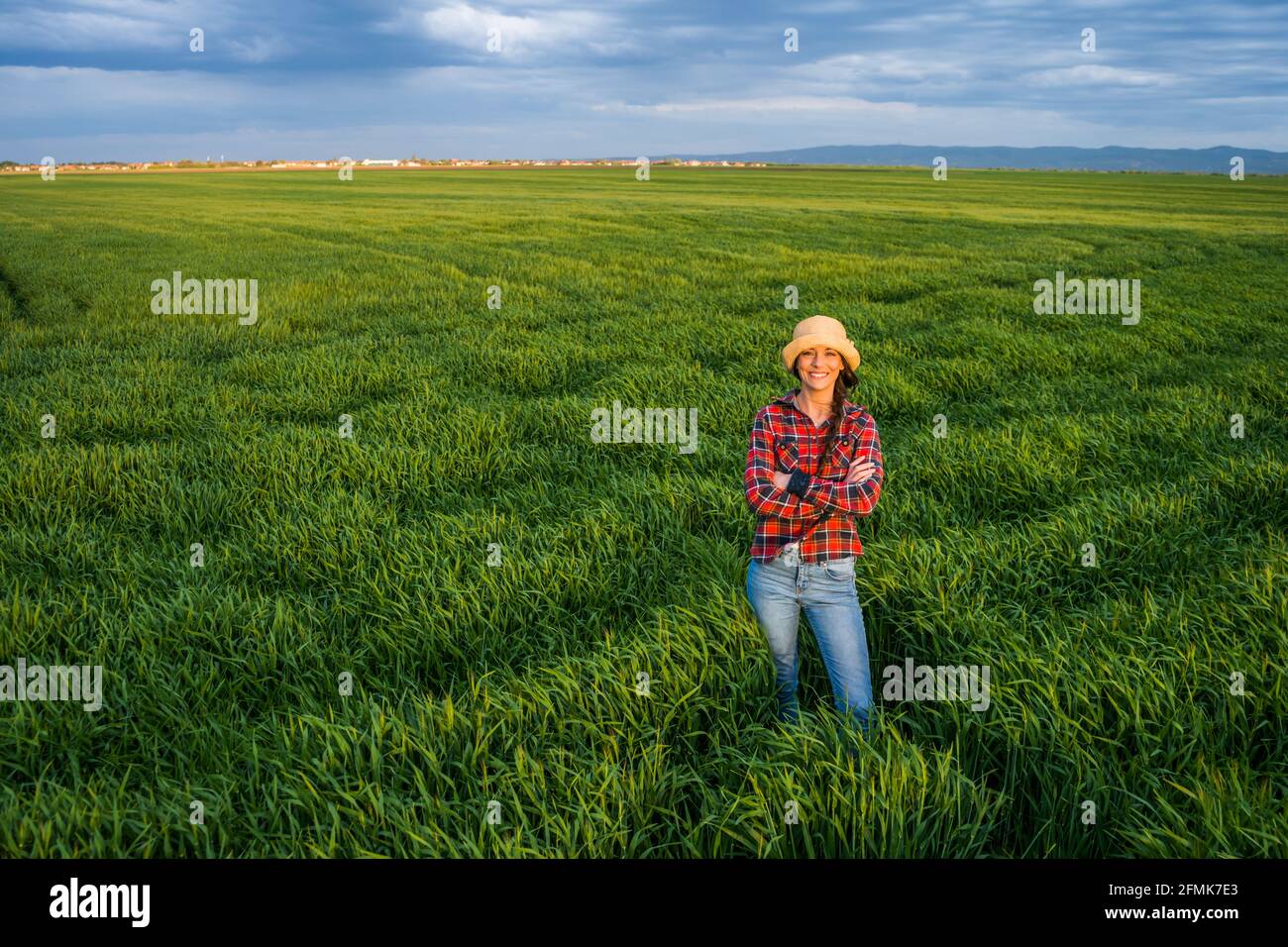 Orgogliosa agricoltore femminile è in piedi nel suo campo di orzo e godendo il tramonto. Foto Stock