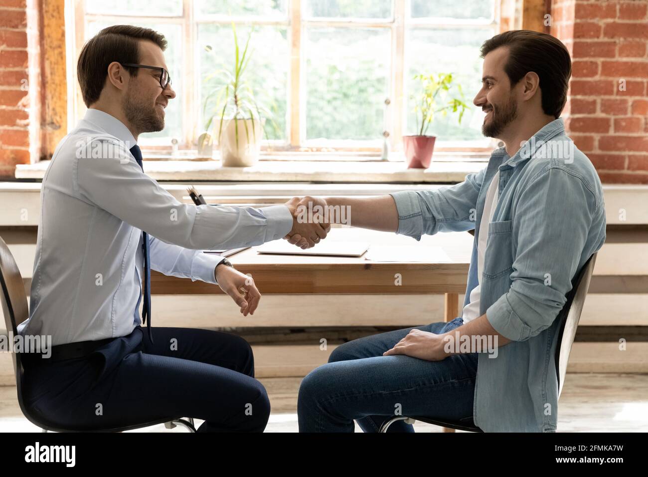 Vista laterale uomini d'affari felici che scuotono le mani, chiudendo l'accordo di successo Foto Stock