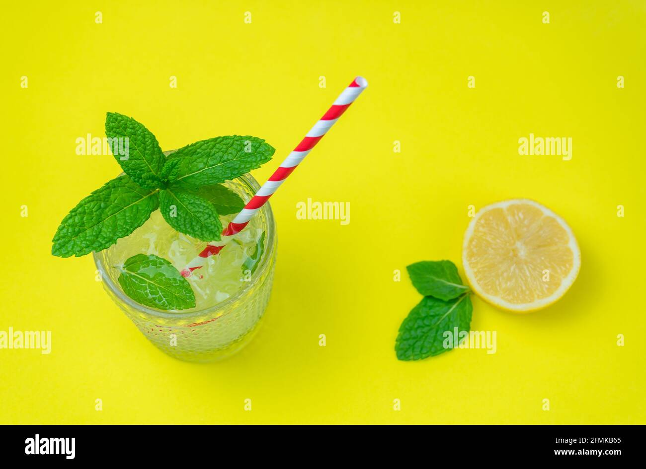 Vista dall'alto di un rinfrescante cocktail mojito con limone fresco e menta verde isolato su sfondo giallo. Summer Tropical studio shot, concetto di party drink. Foto Stock