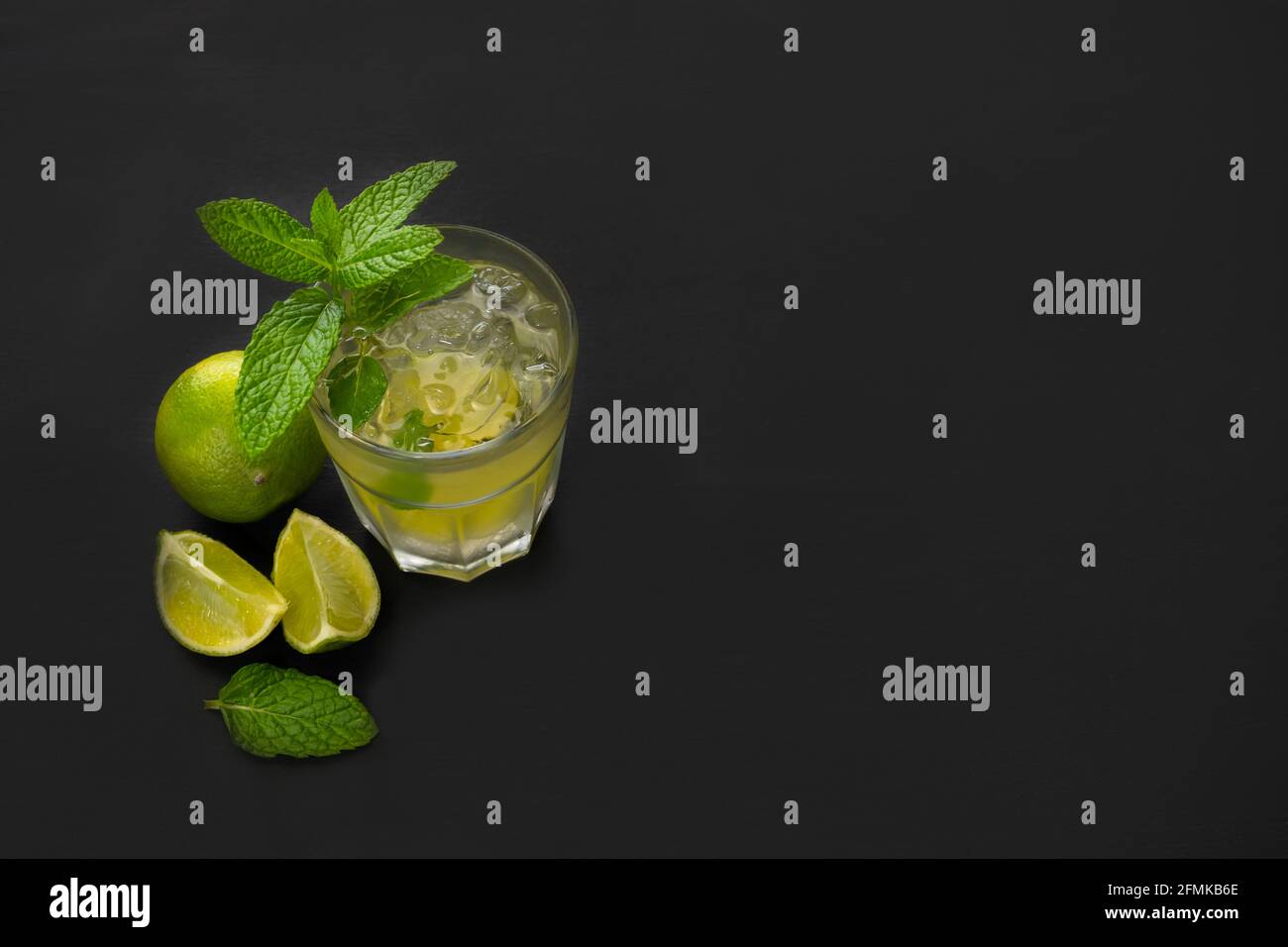 Vista dall'alto del cocktail mojito con lime verdi fresche e menta su sfondo scuro con spazio per la copia di testo o pubblicità. Foto Stock