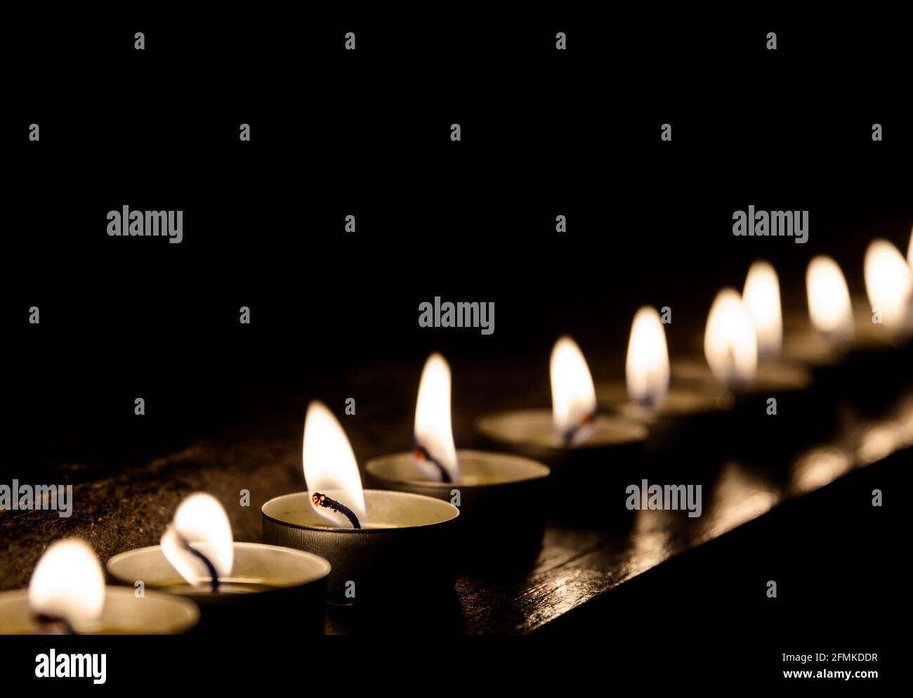 Candele accese di fila di notte Foto Stock